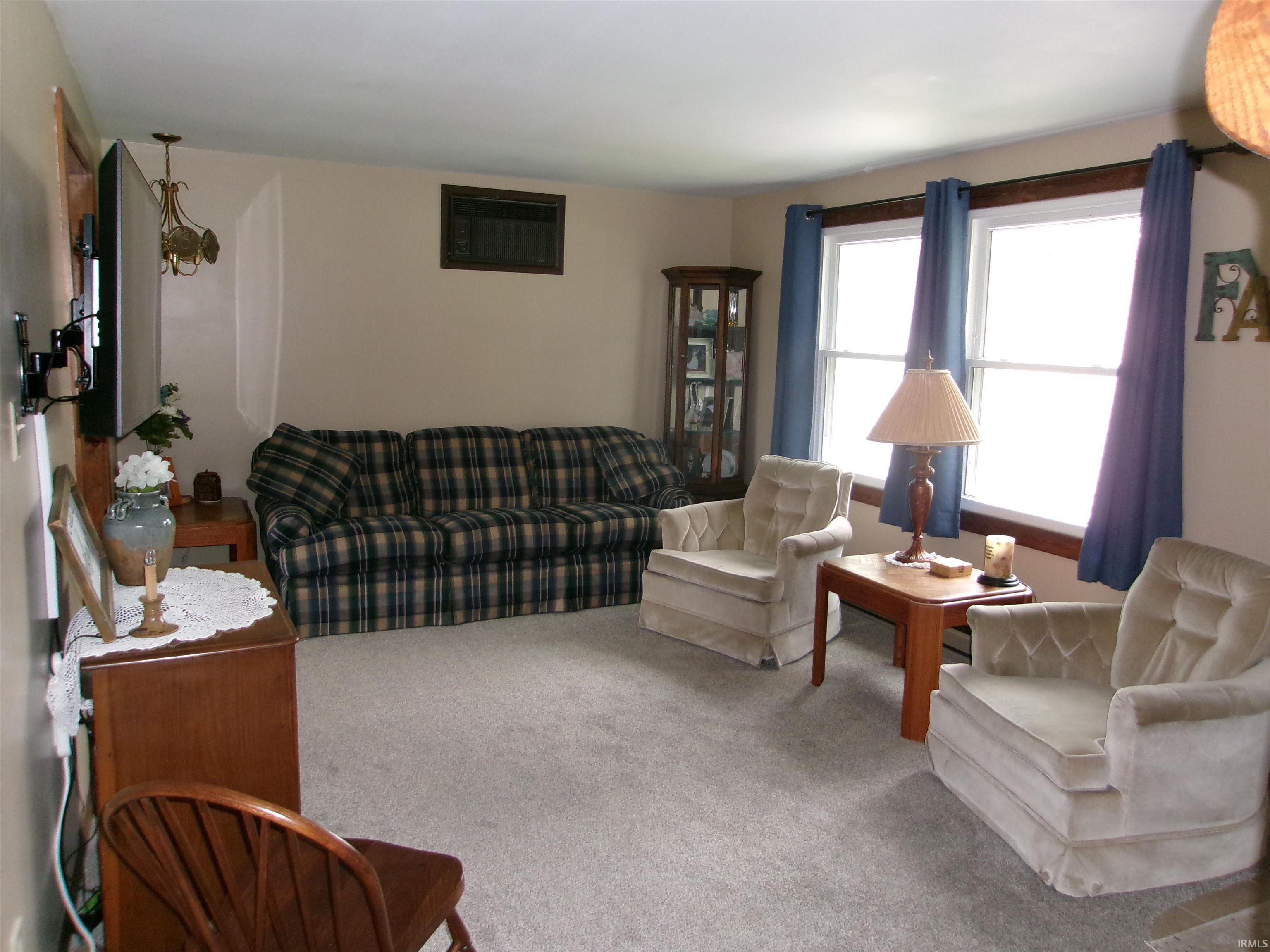 Spacious living area featuring light-toned wall paint and neutral carpet flooring