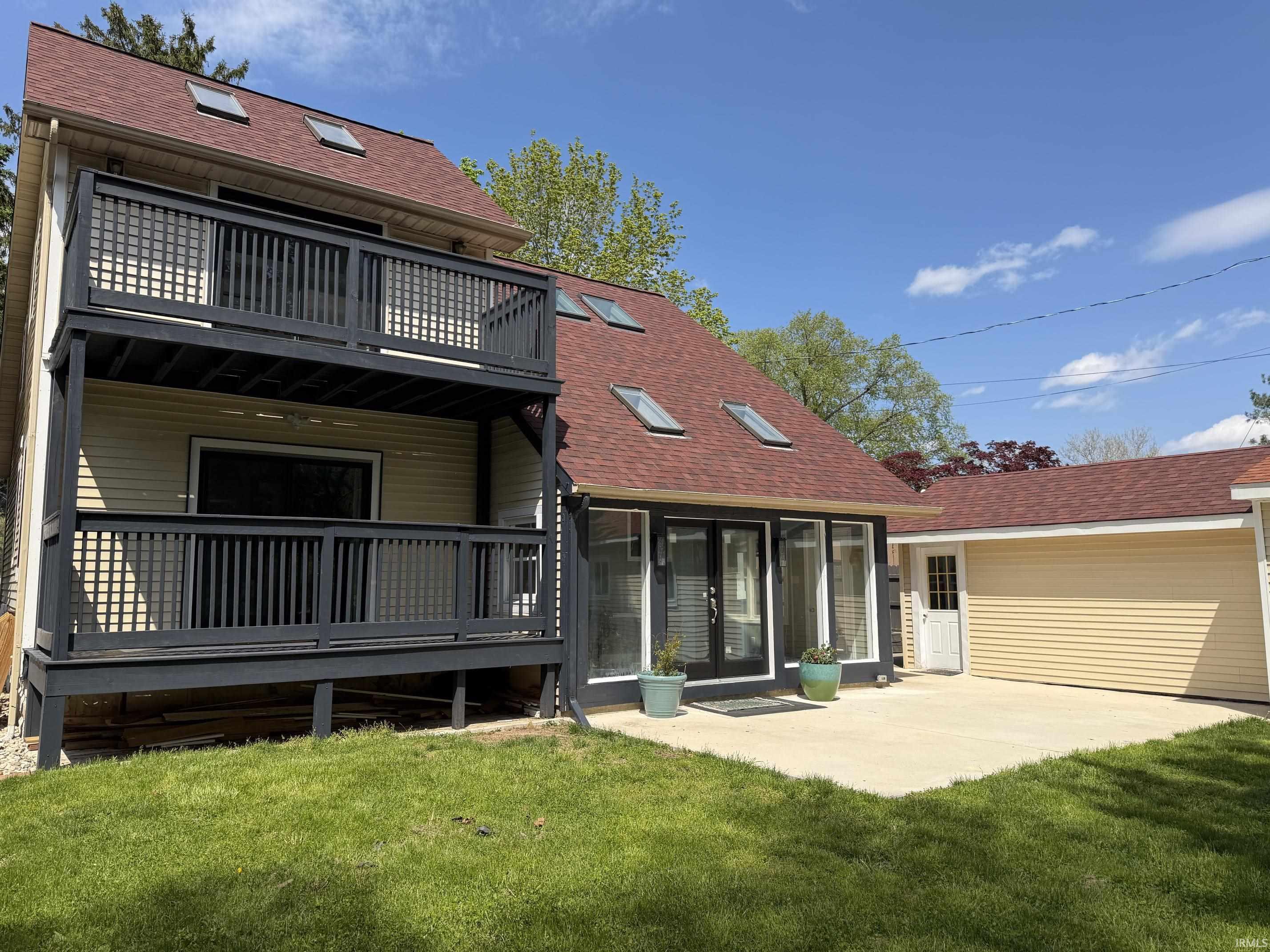 Exterior featuring two levels of dark-toned decks, skylights, and a red shingle roof
