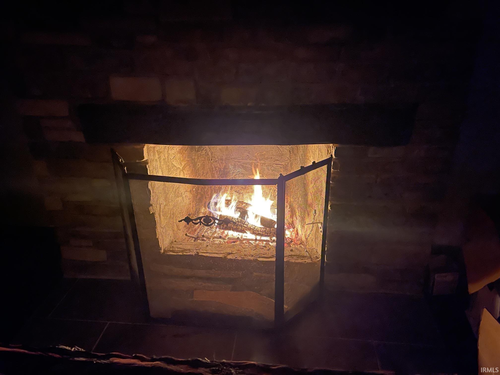 Stone-clad fireplace featuring a dark wood mantel and a metal fireguard