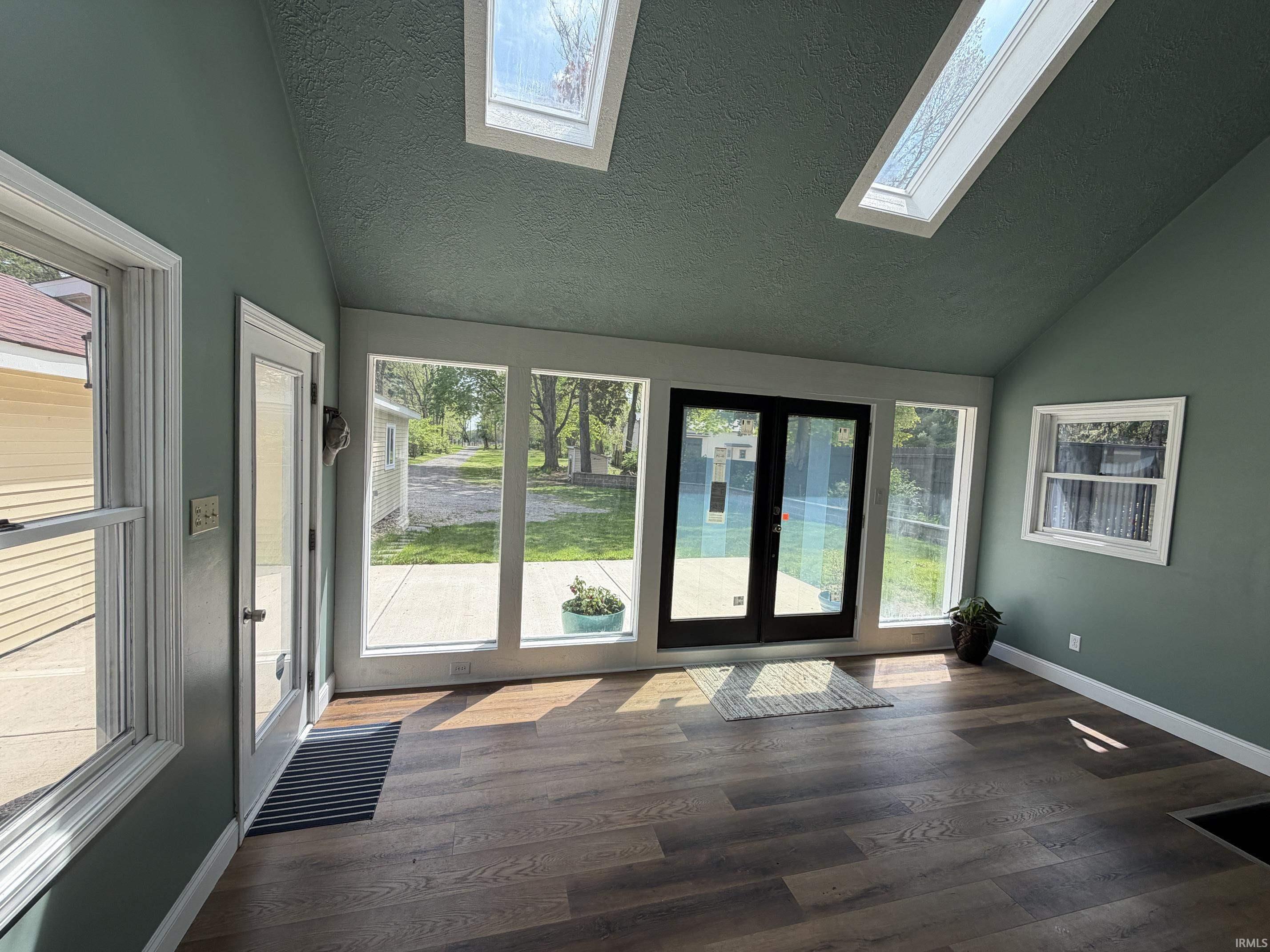 Sunroom featuring wood-finish flooring and a vaulted ceiling with two skylights