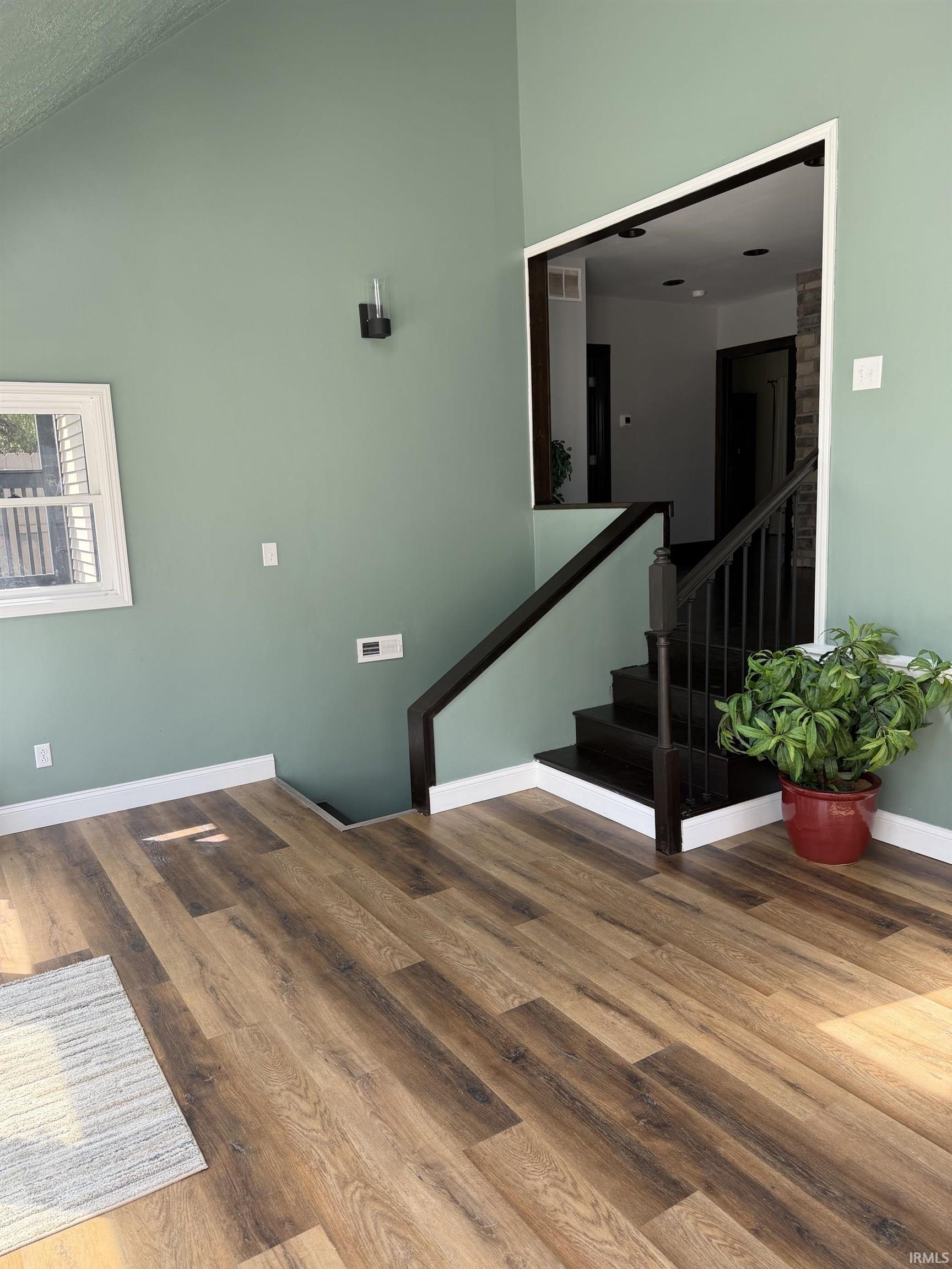 Varnished wood-finish flooring with white baseboards throughout