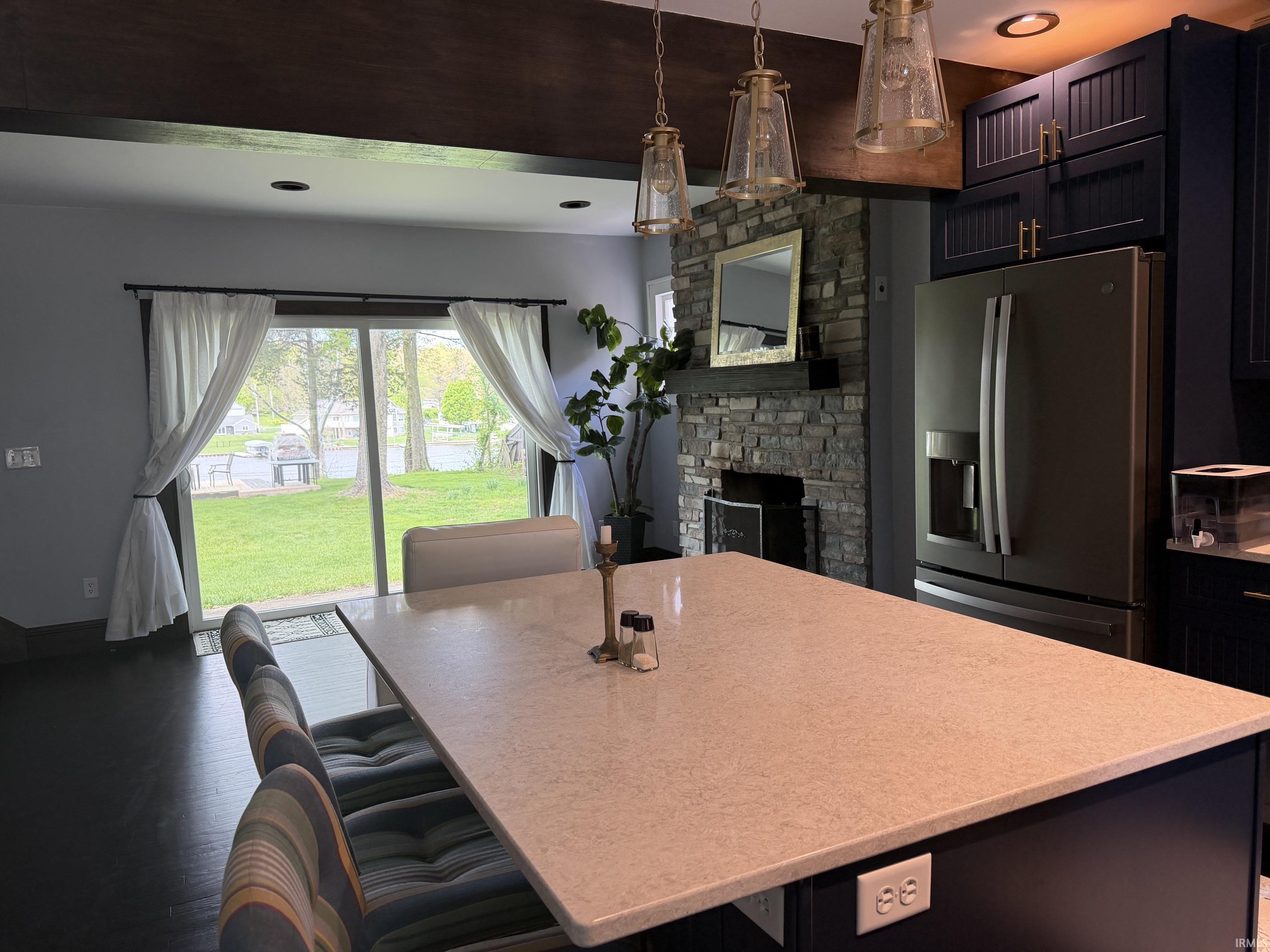 Kitchen island featuring a light-toned countertop, dark cabinetry, and three pendant light fixtures