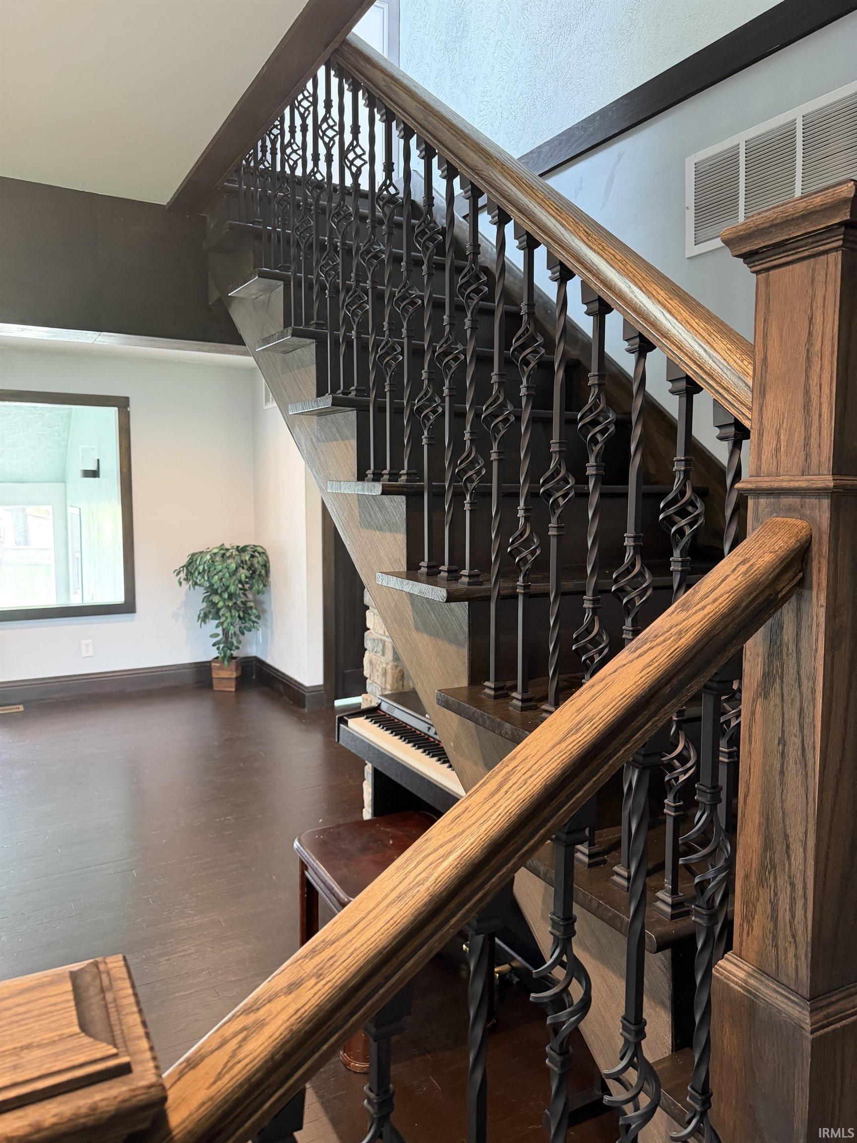 Staircase featuring dark wood treads and handrail with decorative wrought iron balusters