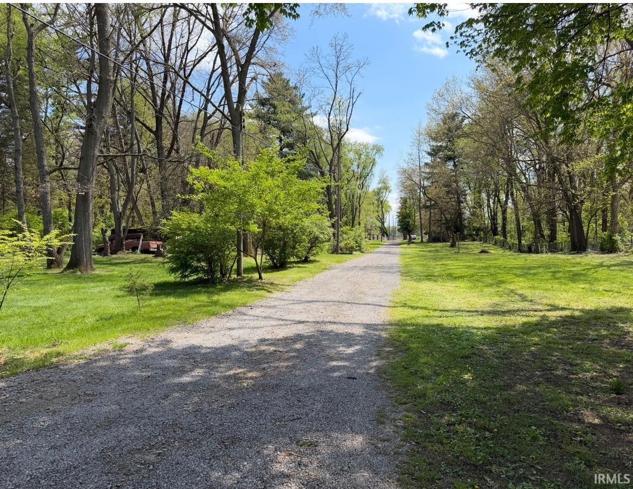 Gravel pathway framed by expansive green lawns and mature trees