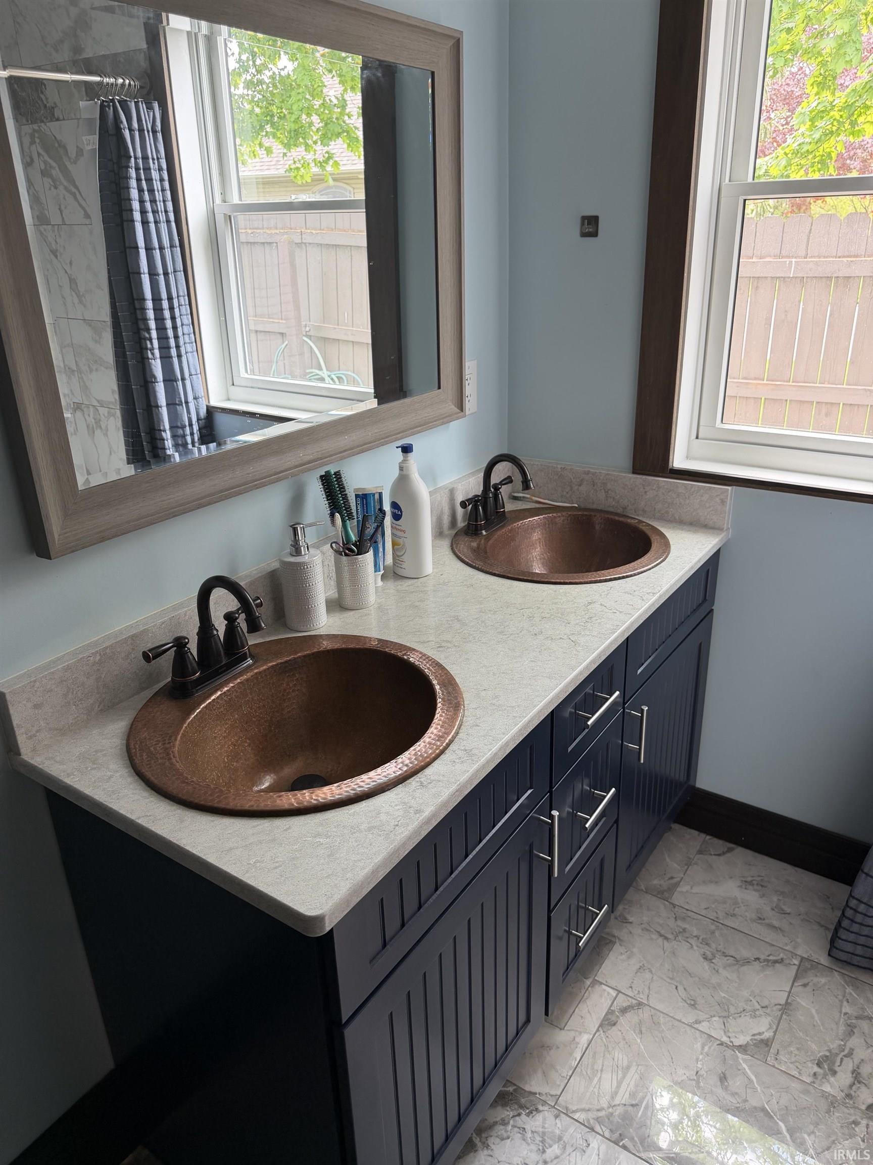Double vanity with hammered copper vessel sinks, oil-rubbed bronze faucets, and a light-toned countertop