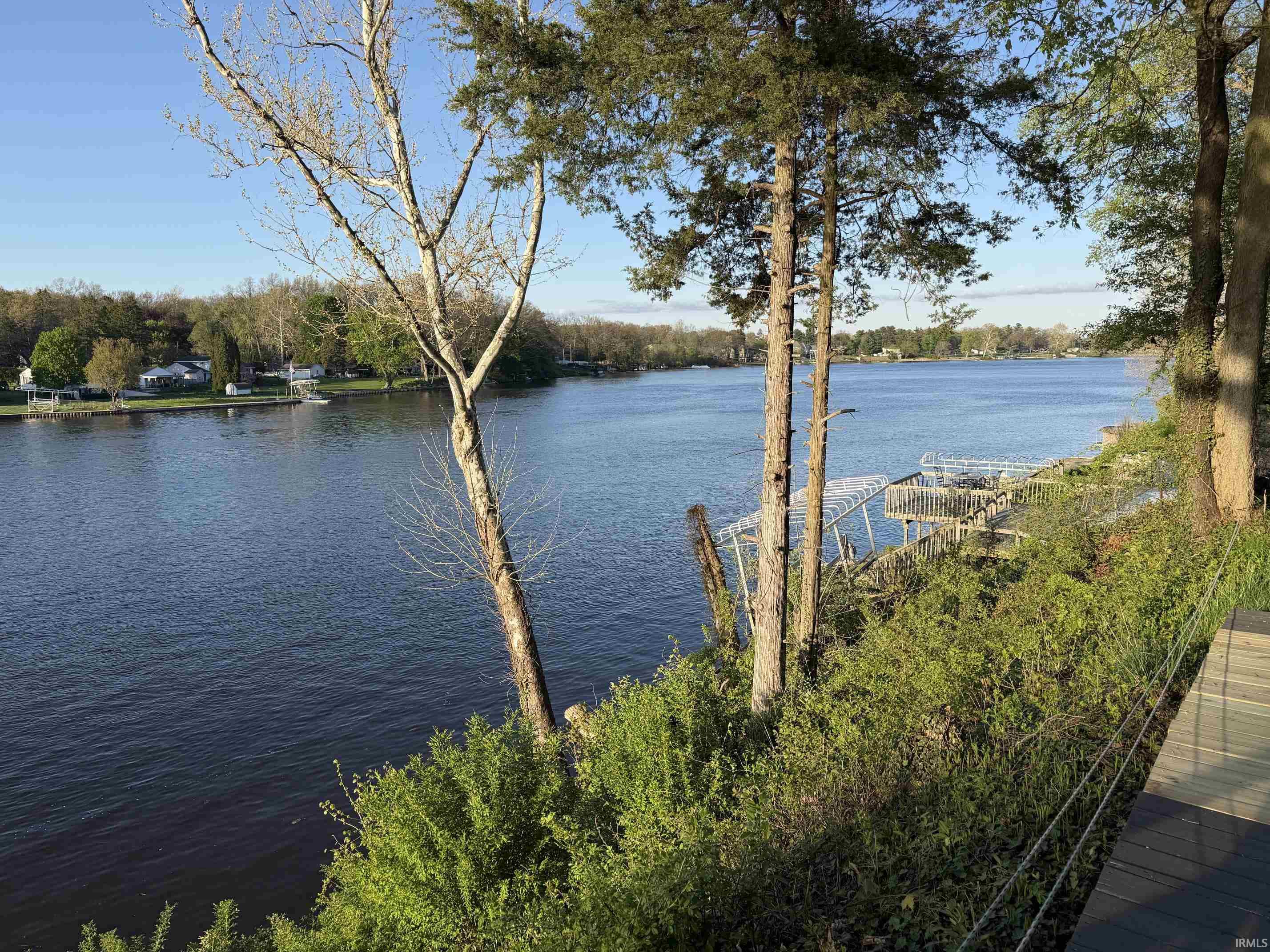 Waterfront property featuring extensive water frontage, multiple boat docks, mature trees, and a wooden deck
