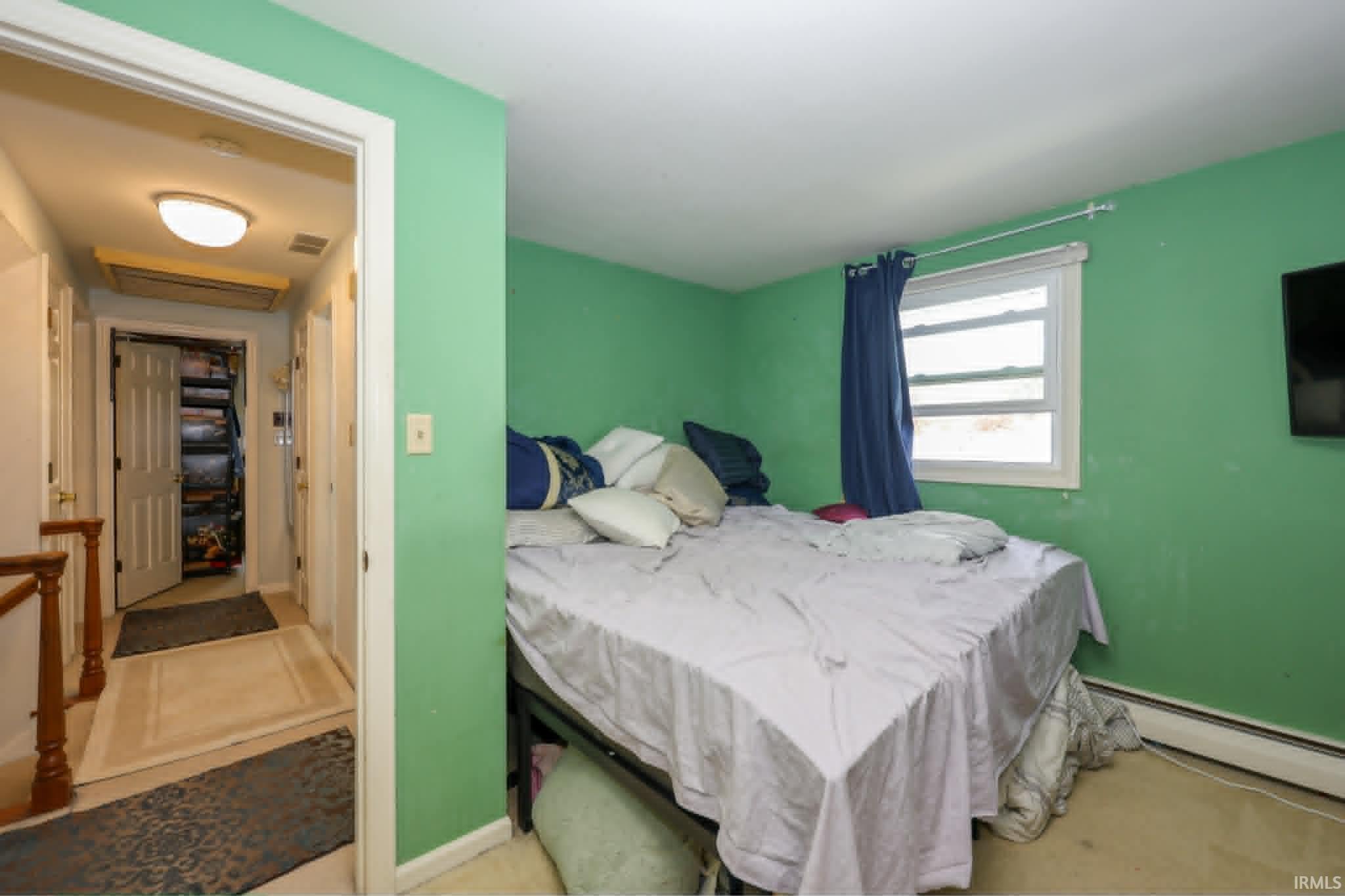 Bedroom featuring a window with white trim, green painted walls, and light-colored carpet flooring