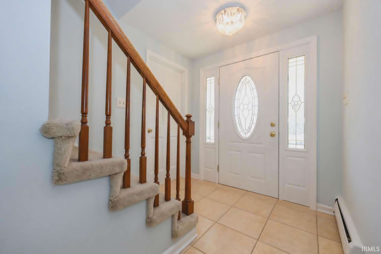 Entryway featuring a white door with oval decorative glass, flanked by two sidelights with patterned glass