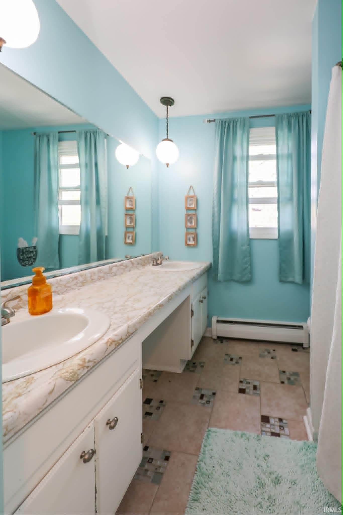 Bathroom with a dual sink vanity featuring white cabinetry and a patterned countertop
