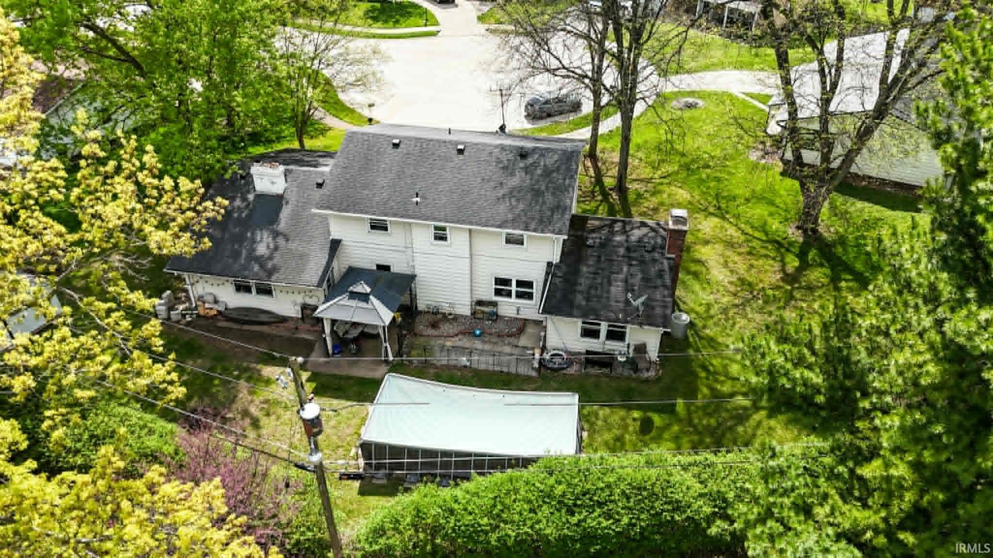 White siding home featuring a dark shingle roof, rear patio, and a covered gazebo