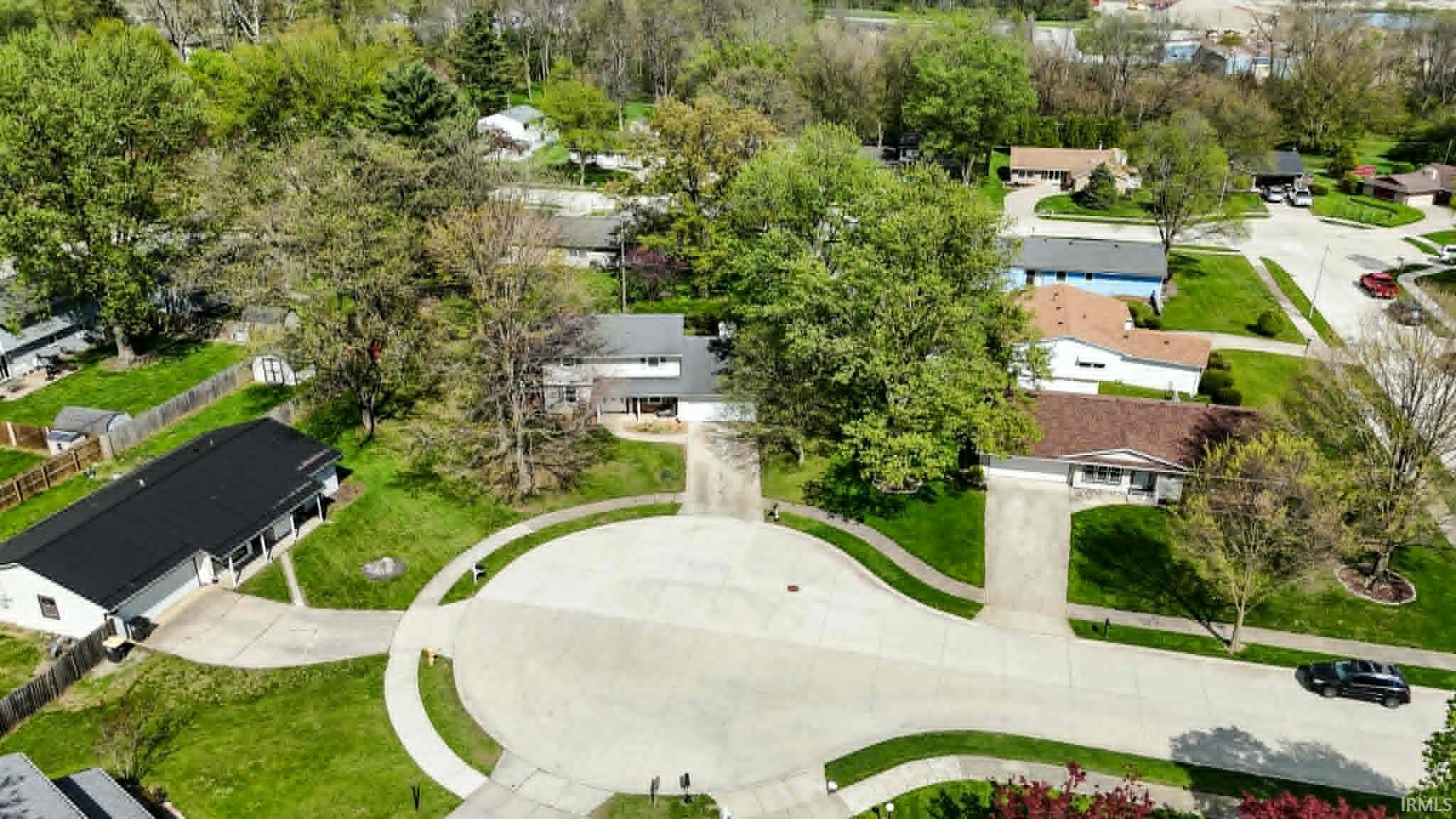 Residential neighborhood with mature trees, established landscaping, cul-de-sac street pattern, and paved driveways