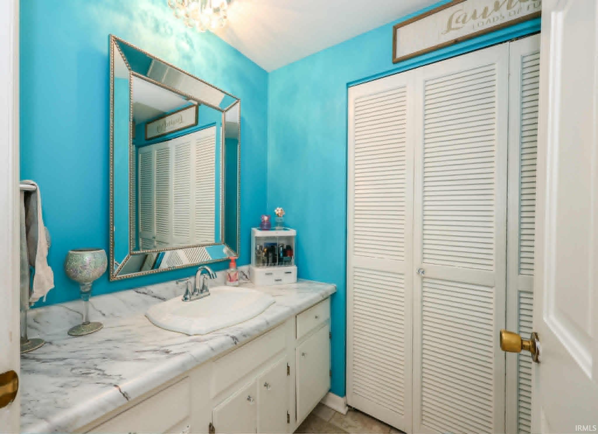 Bathroom vanity featuring a white countertop with integrated sink, chrome-finish faucet, and a large framed mirror