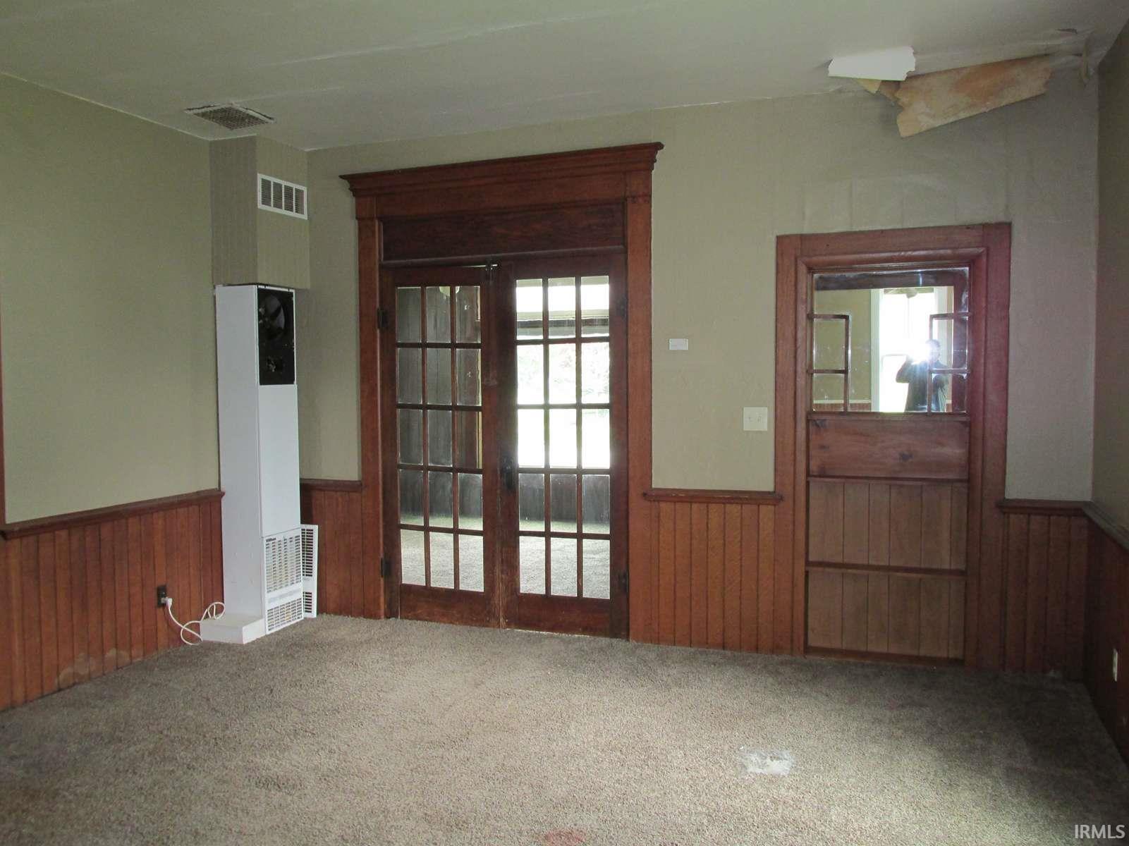 Room featuring wood-finish wainscoting, neutral wall paint, and carpeted flooring
