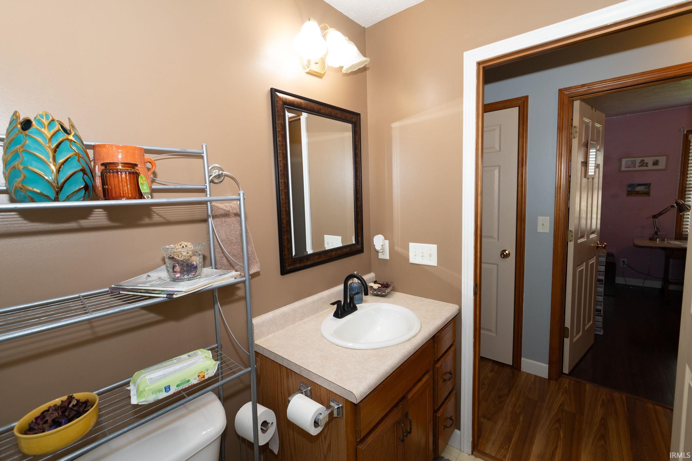 Bathroom vanity with a white oval sink, dark countertop, and wood-finish cabinetry