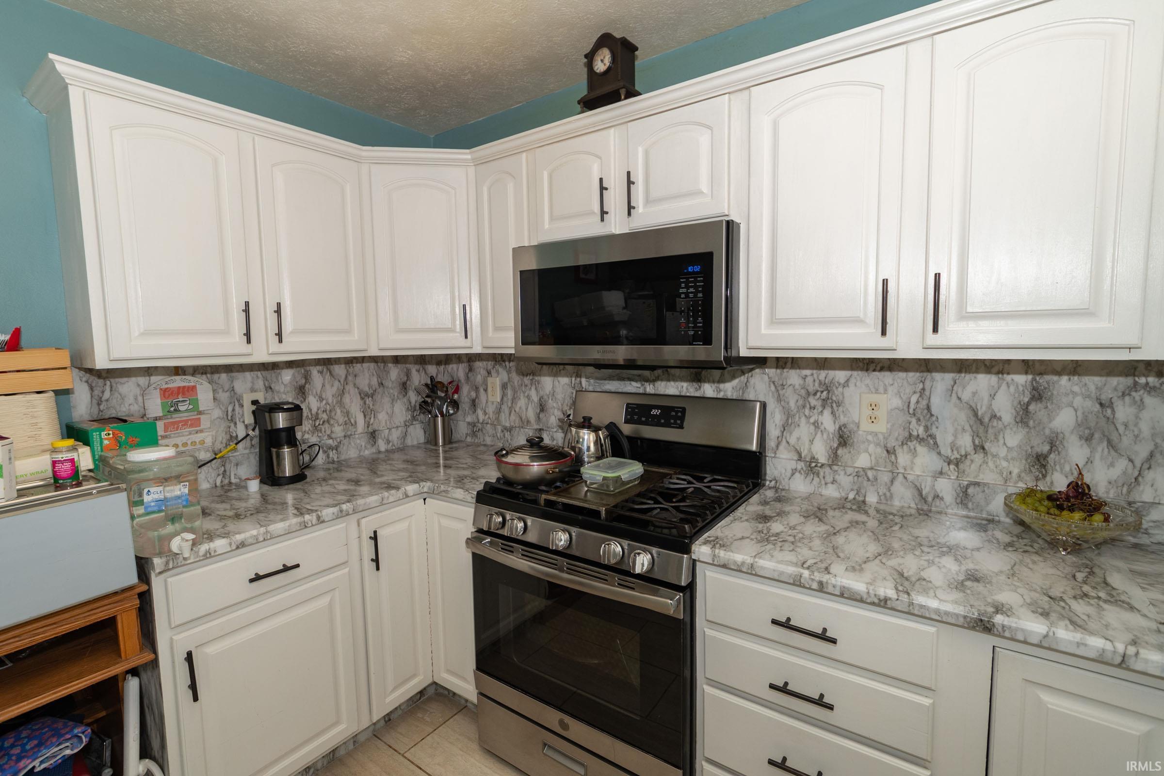 Kitchen featuring white cabinetry with dark hardware, a stainless steel range, and an over-the-range microwave