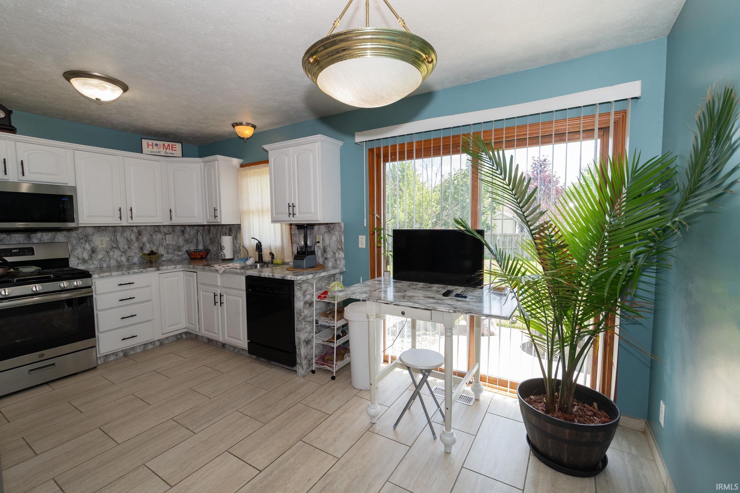 Kitchen featuring white cabinetry, grey-patterned countertops, and a matching backsplash