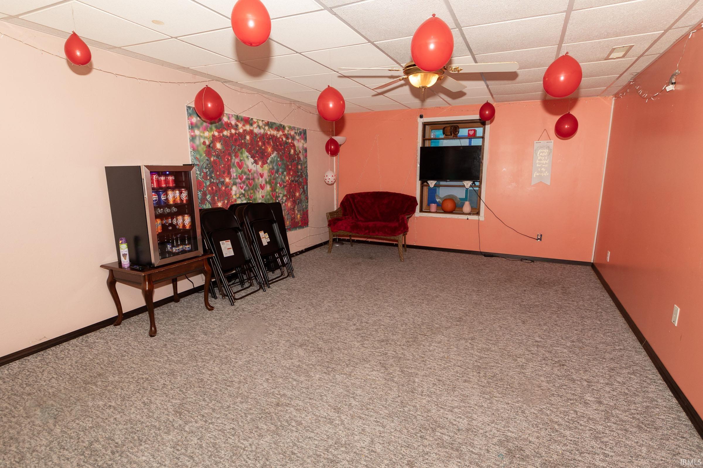 Carpeted interior space with a dropped ceiling and ceiling fan