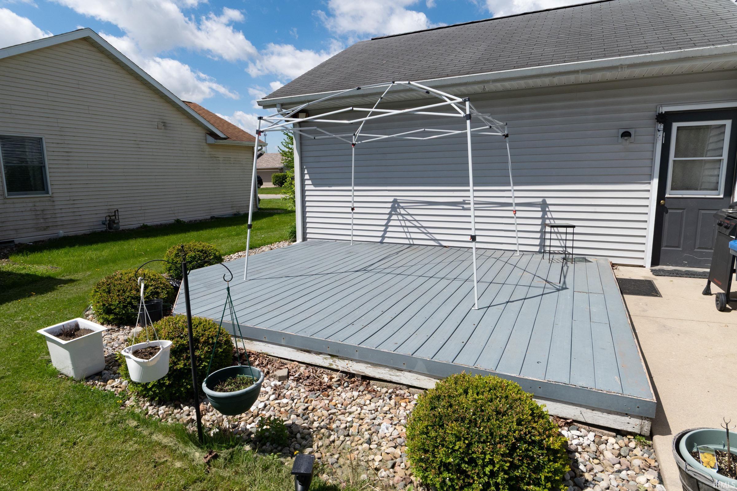 Gray wood-finish deck with surrounding landscaping featuring gravel and shrubs