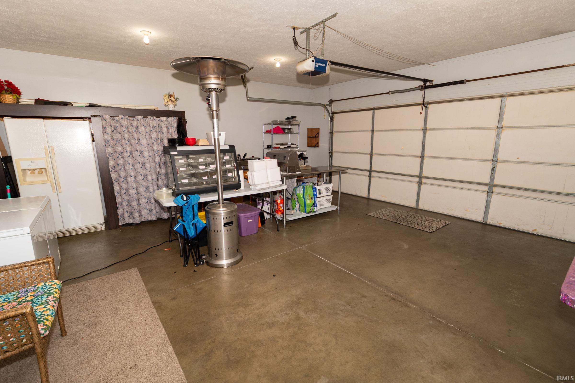 Spacious garage featuring a large overhead door, concrete flooring, and ceiling-mounted lighting