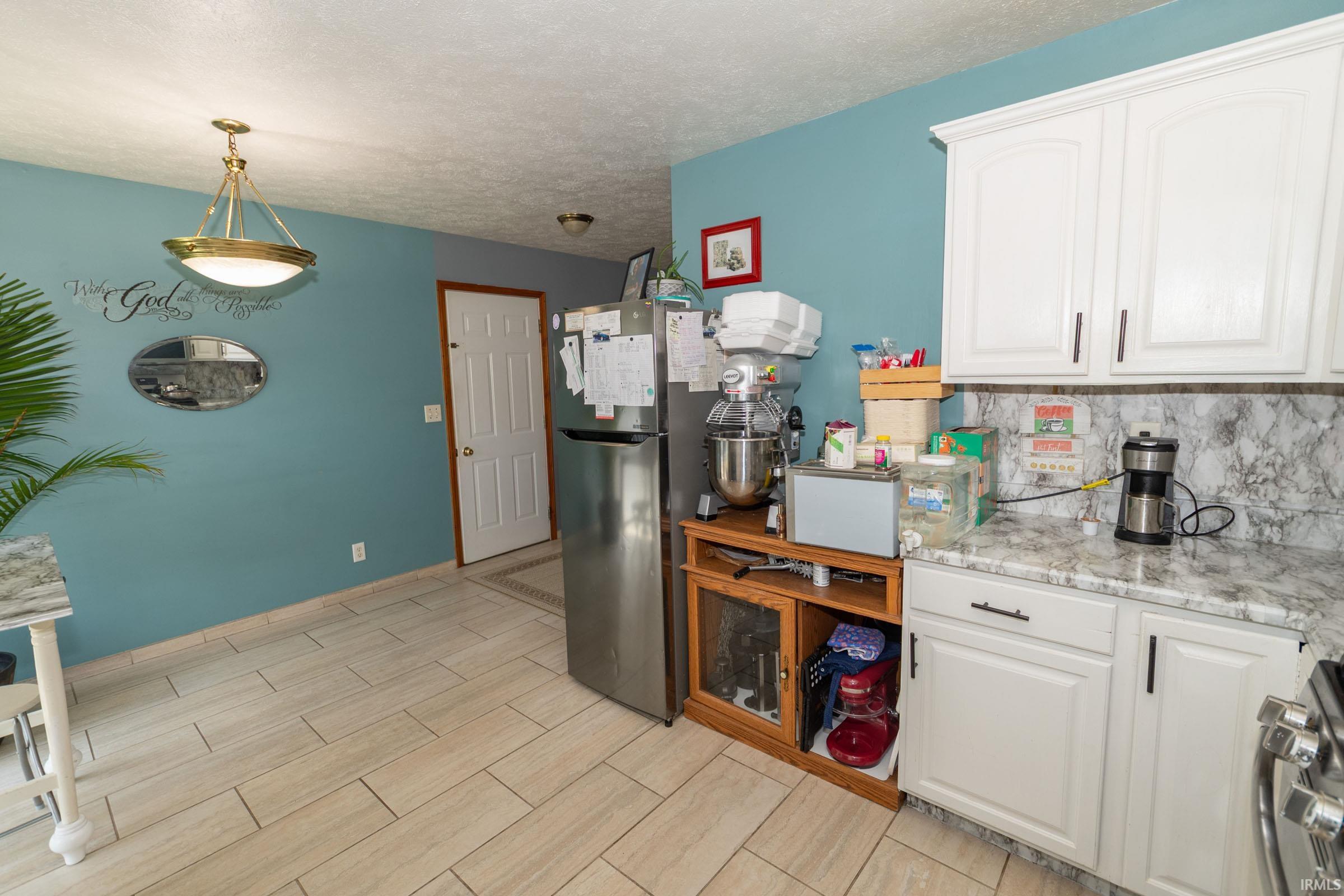 Kitchen featuring white cabinetry with dark hardware, stone-look countertops, and a coordinating stone-look backsplash