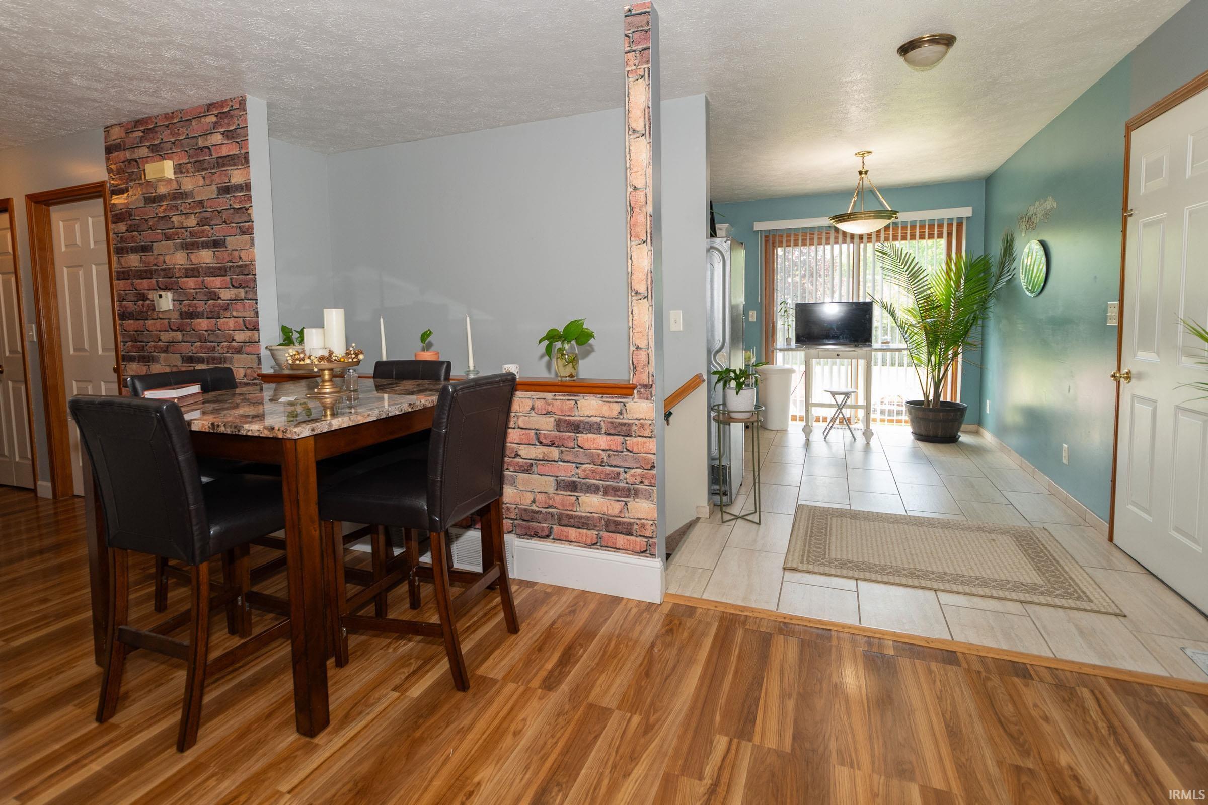 Dining area featuring wood-finish flooring and a partial brick-look accent wall