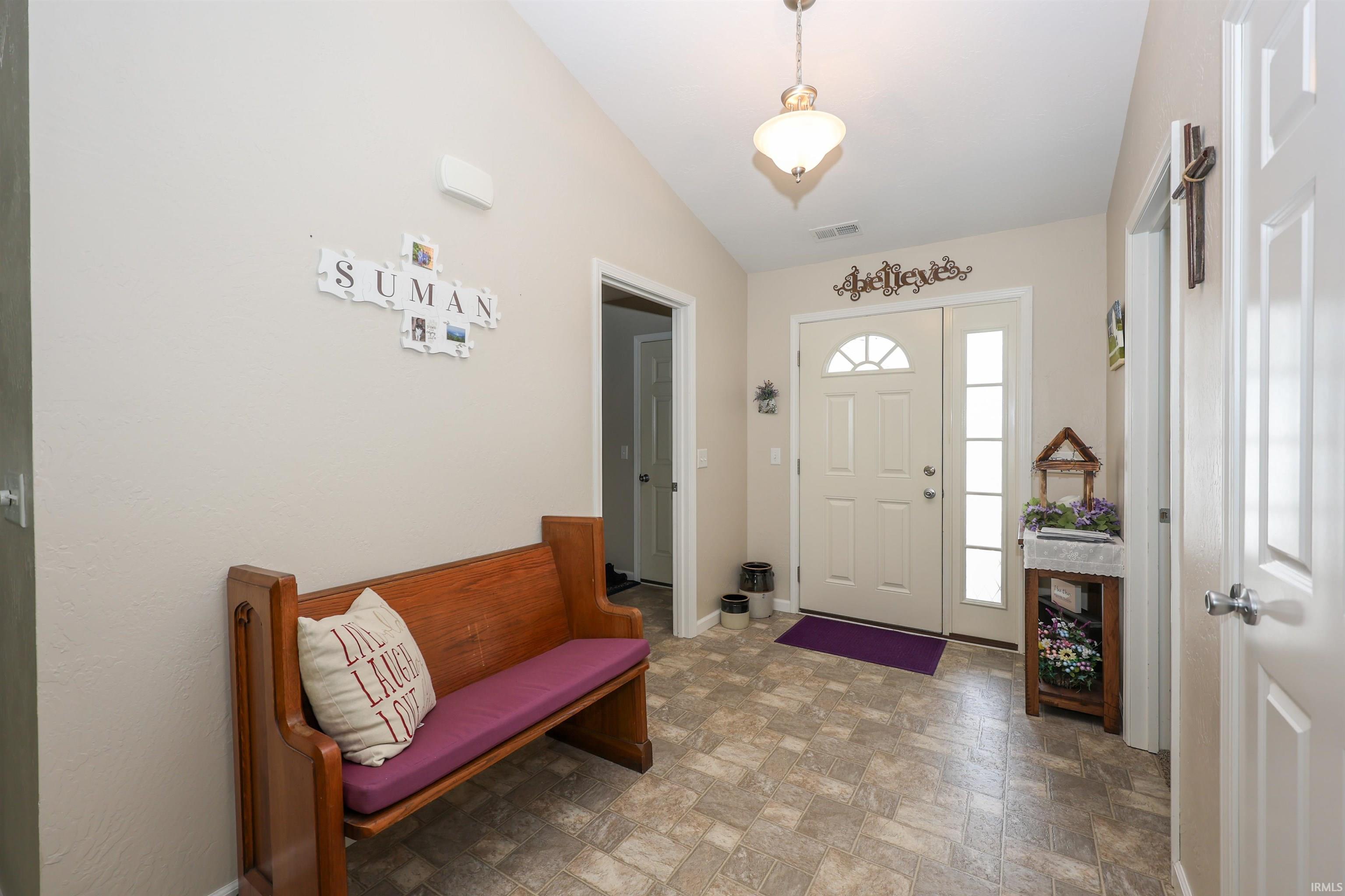 Entryway featuring a vaulted ceiling with a semi-flush mount light fixture, neutral wall paint, and a white front door with a decorative fanlight and an adjacent sidelight