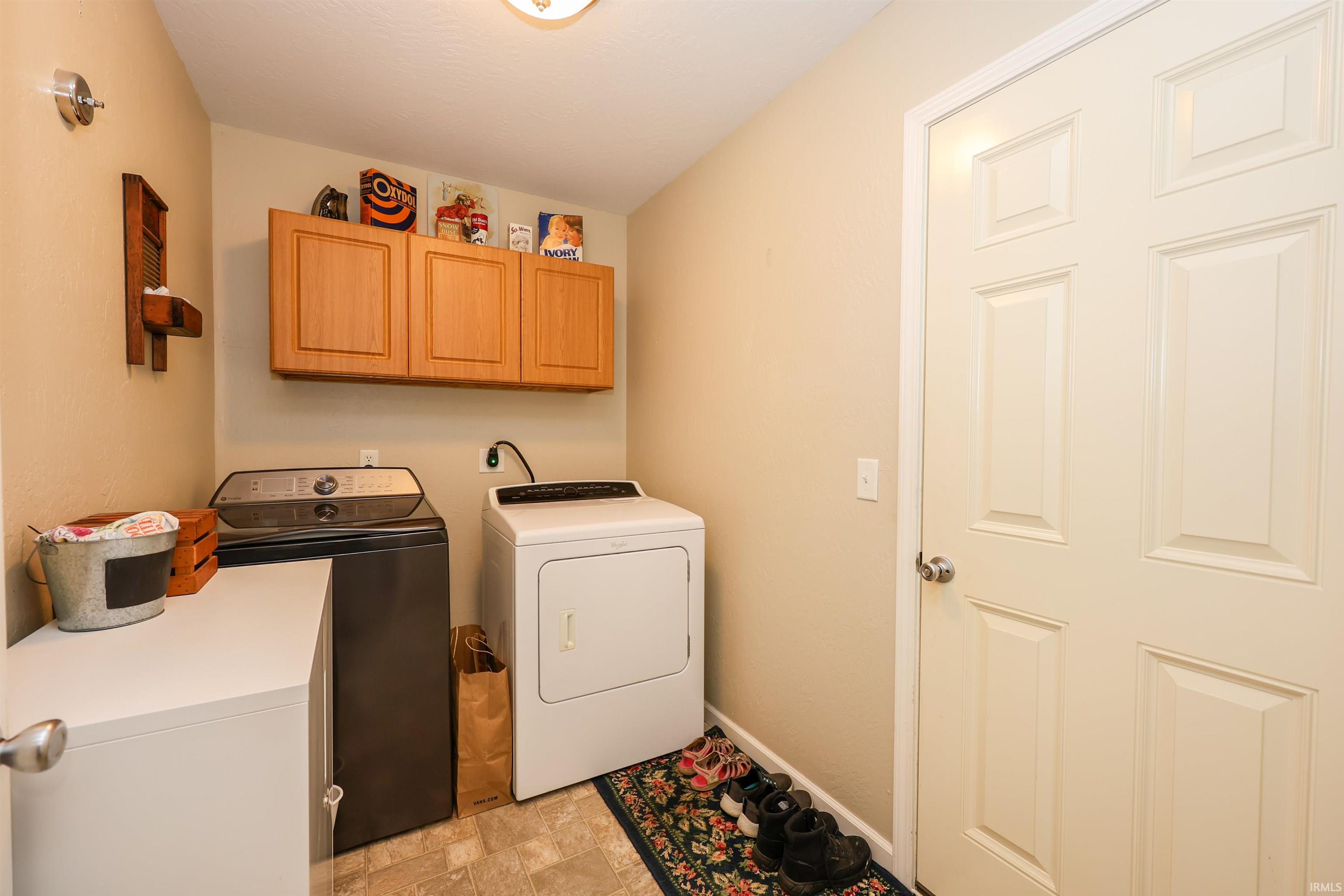 Dedicated laundry space featuring overhead wood-finish cabinetry, a utility counter, and durable flooring