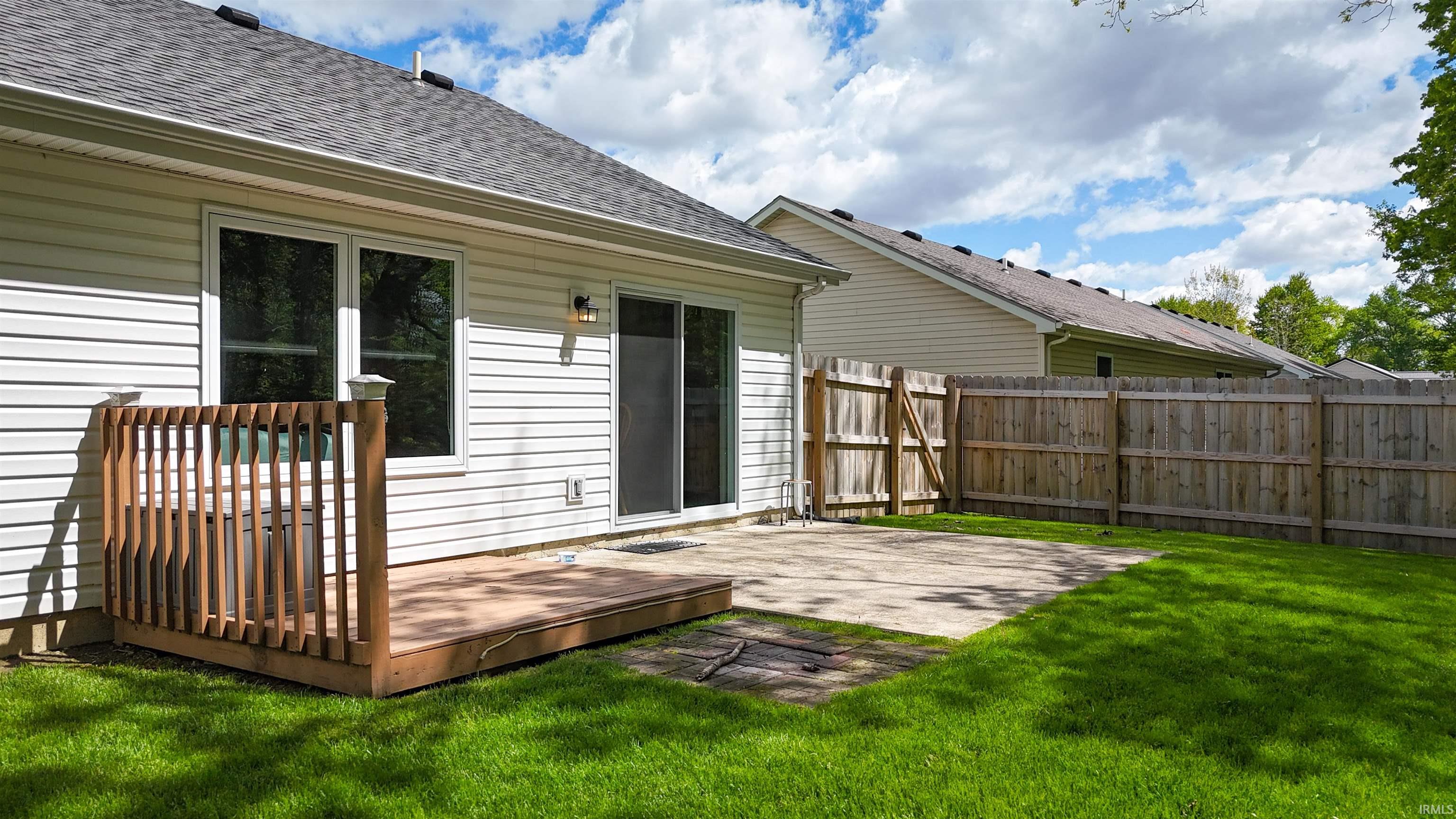Private backyard featuring a wooden deck, concrete patio, and mature wooden privacy fencing