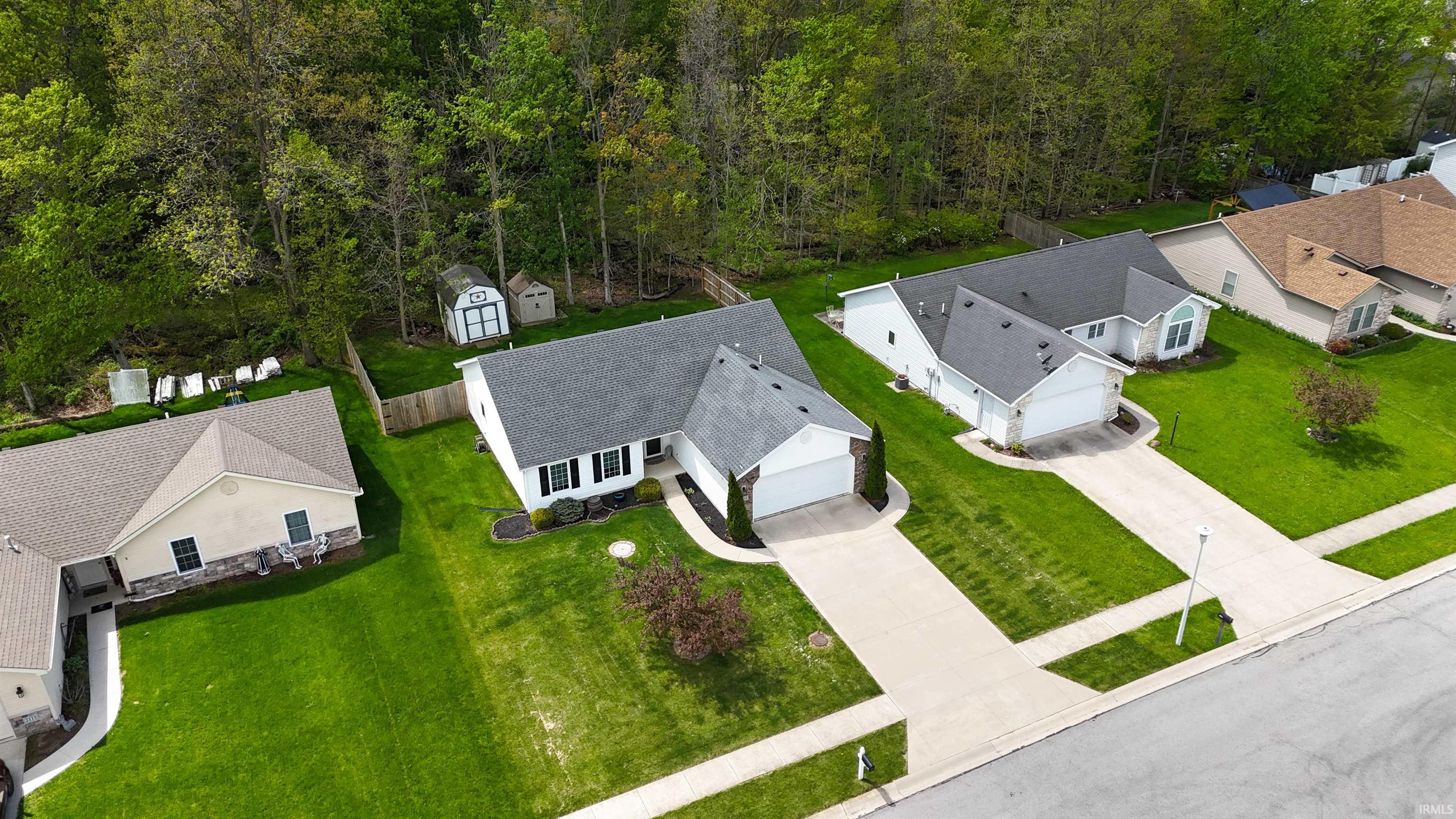 White ranch-style home featuring a dark shingle roof, attached two-car garage, concrete driveway, and manicured front lawn