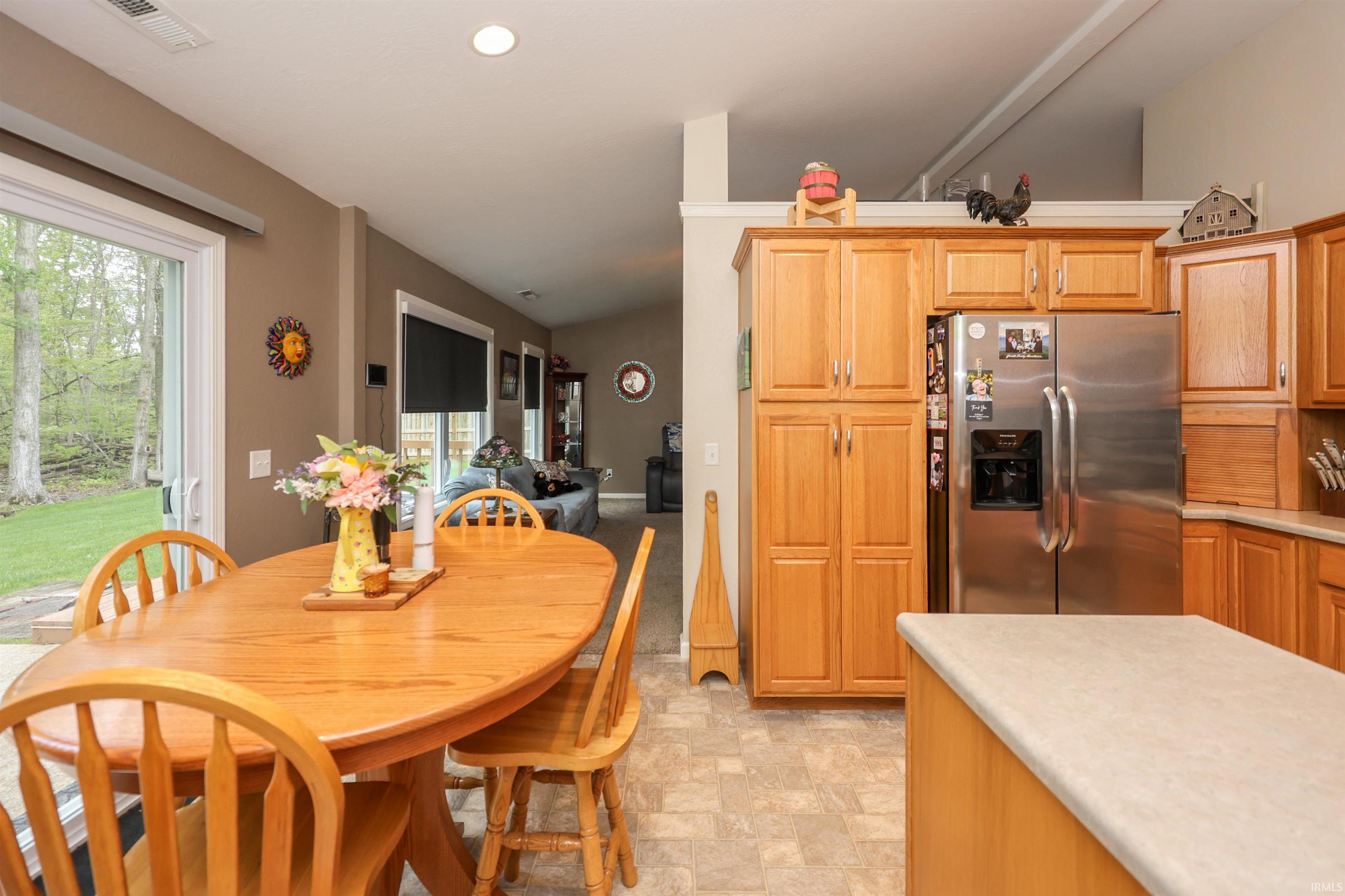 Kitchen area featuring light wood cabinetry, a stainless steel side-by-side refrigerator, and a light-colored countertop