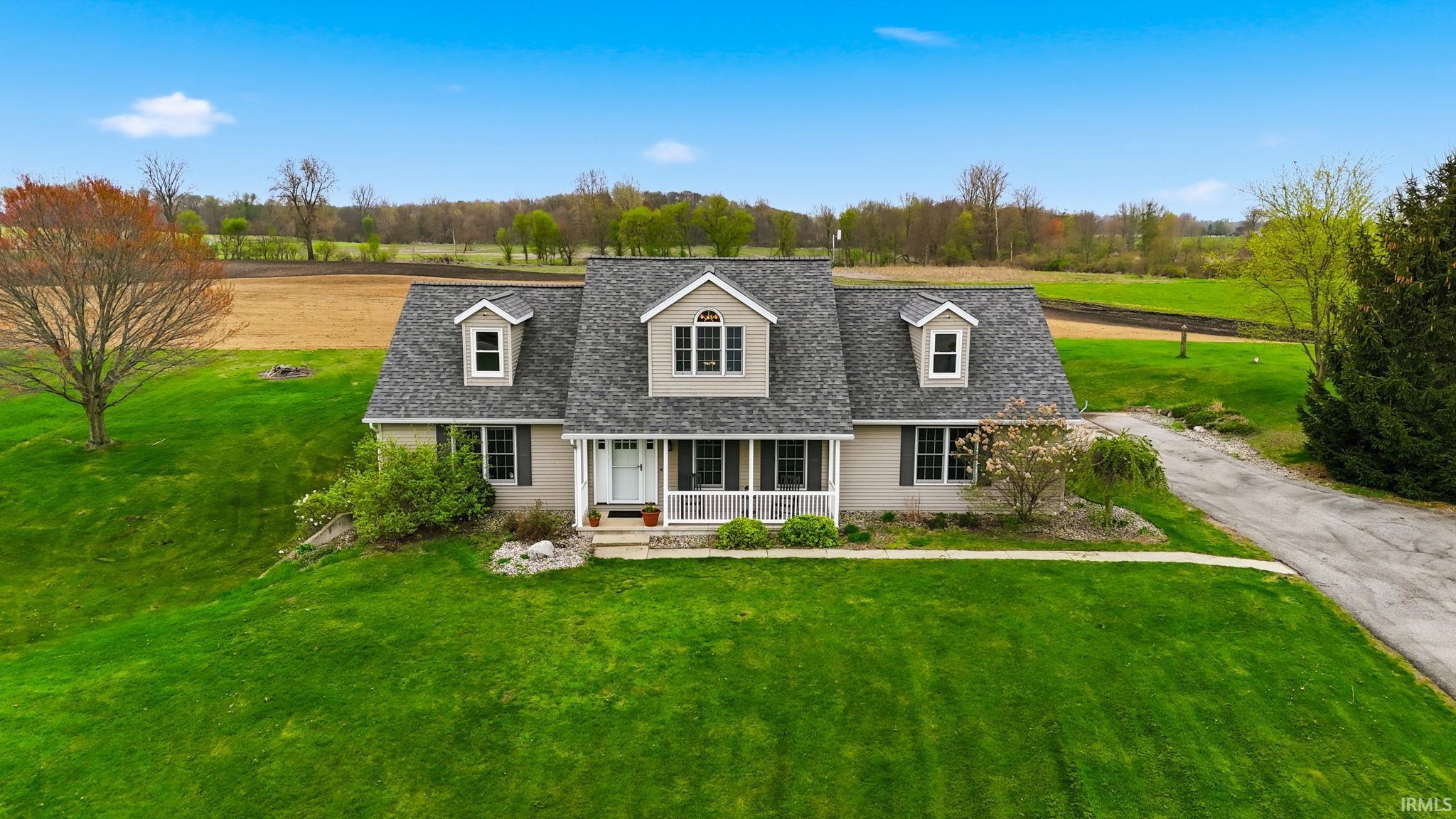 Ranch-style residence featuring a covered front porch, dormer windows, and an attached garage
