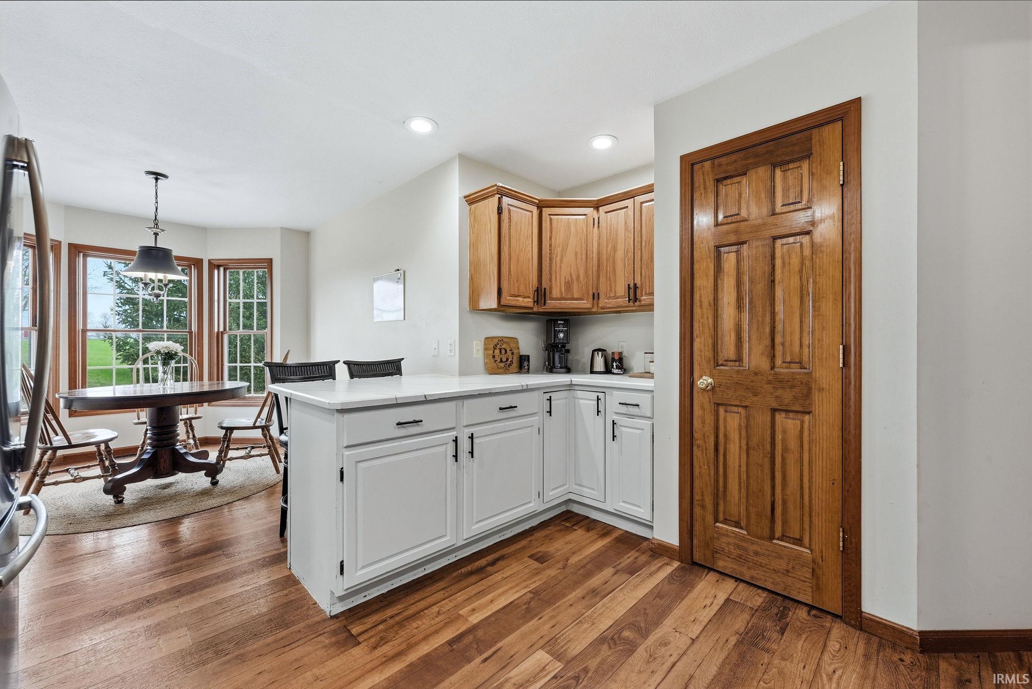 Kitchen space featuring wood-finish flooring and a white kitchen island with counter seating