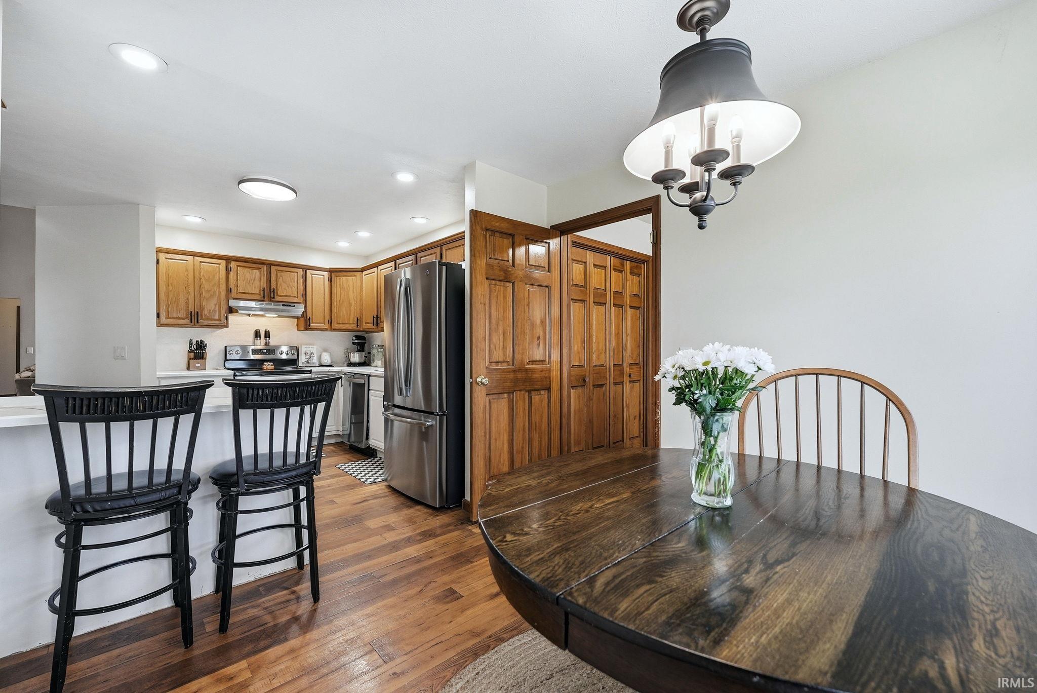 Open-concept dining area featuring wood-finish flooring, a contemporary chandelier, and a breakfast bar with seating