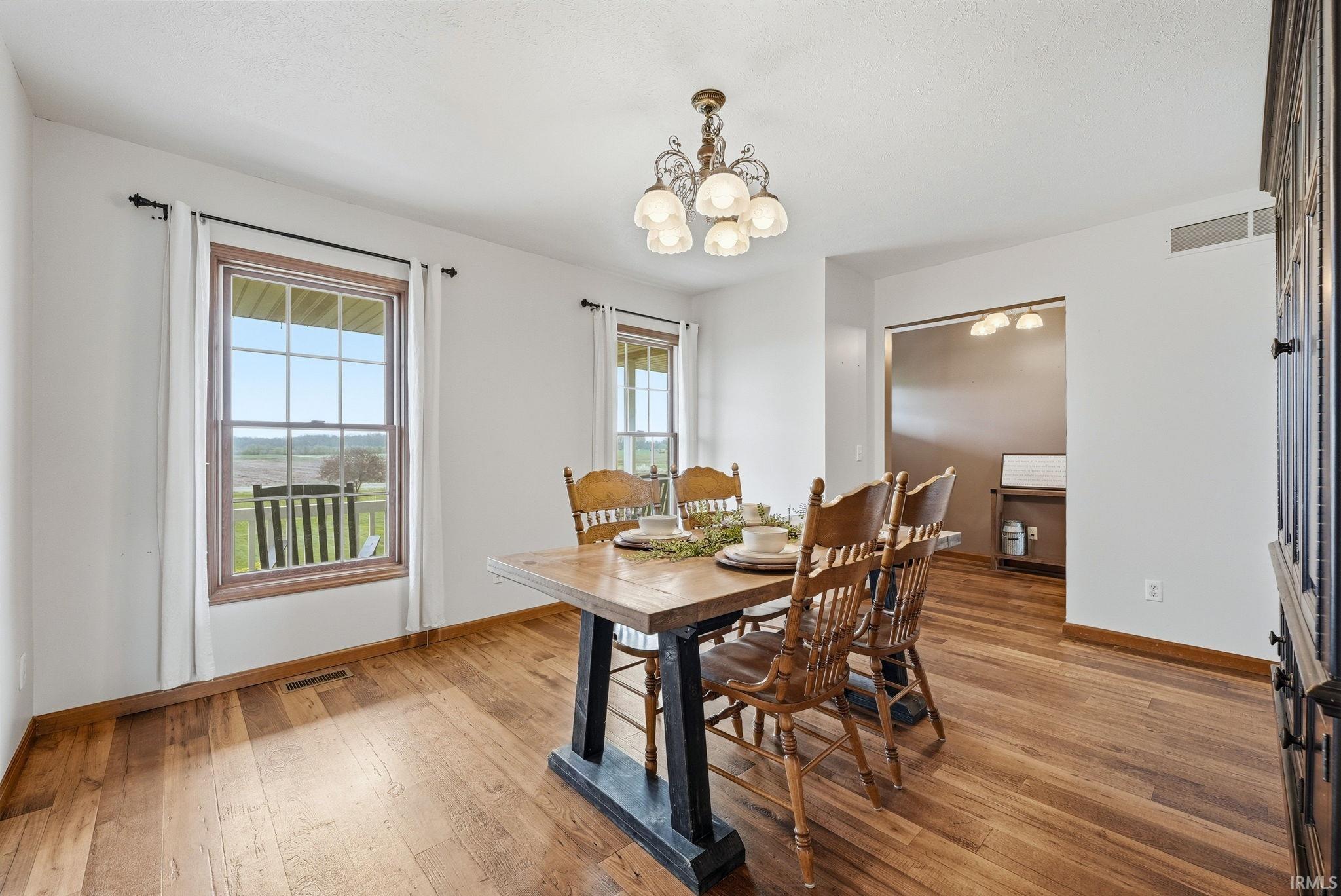 Dining area featuring wood-finish flooring, white walls, and a chandelier with decorative glass shades
