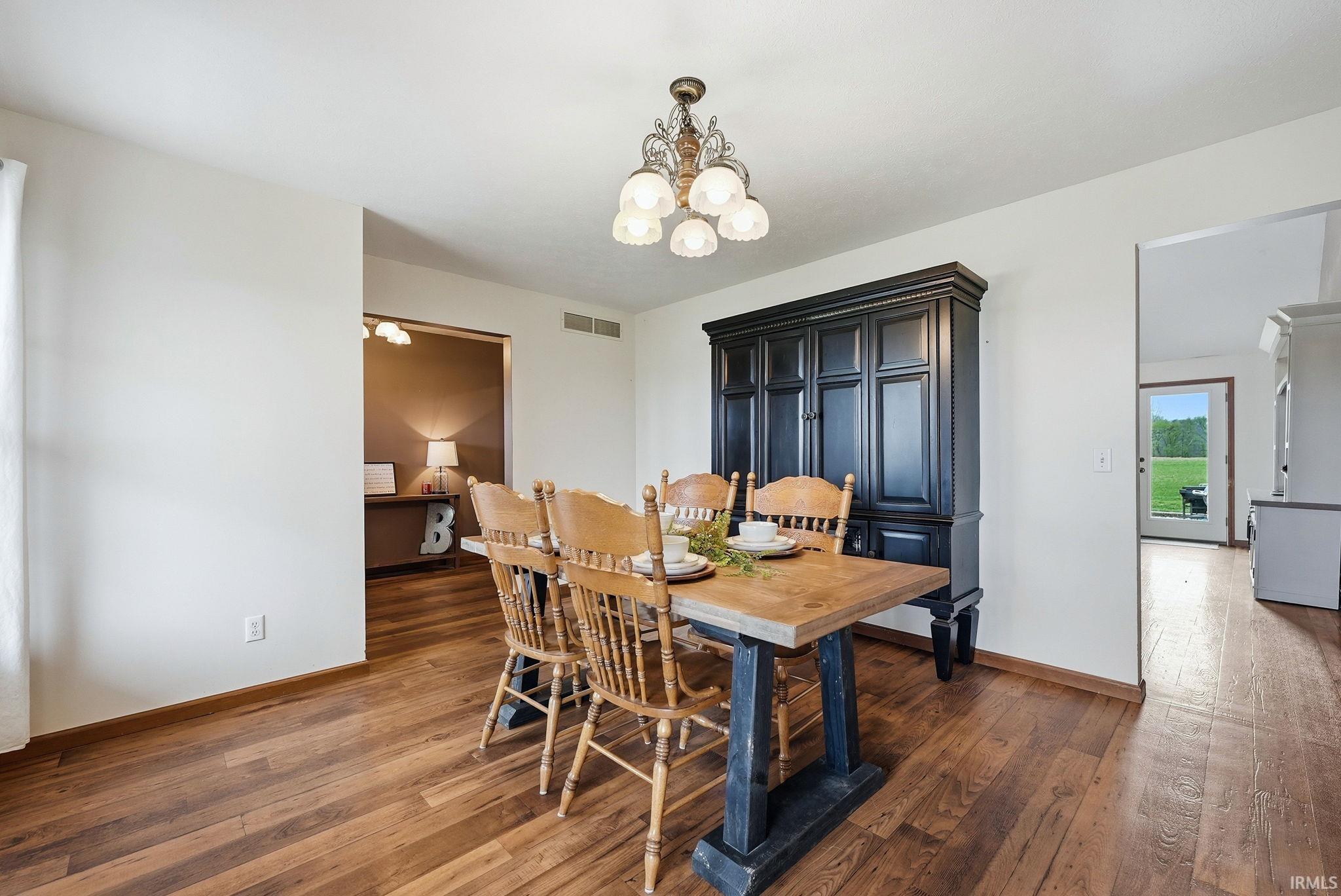 Spacious room with wood-finish flooring, white walls, and a decorative ceiling light fixture
