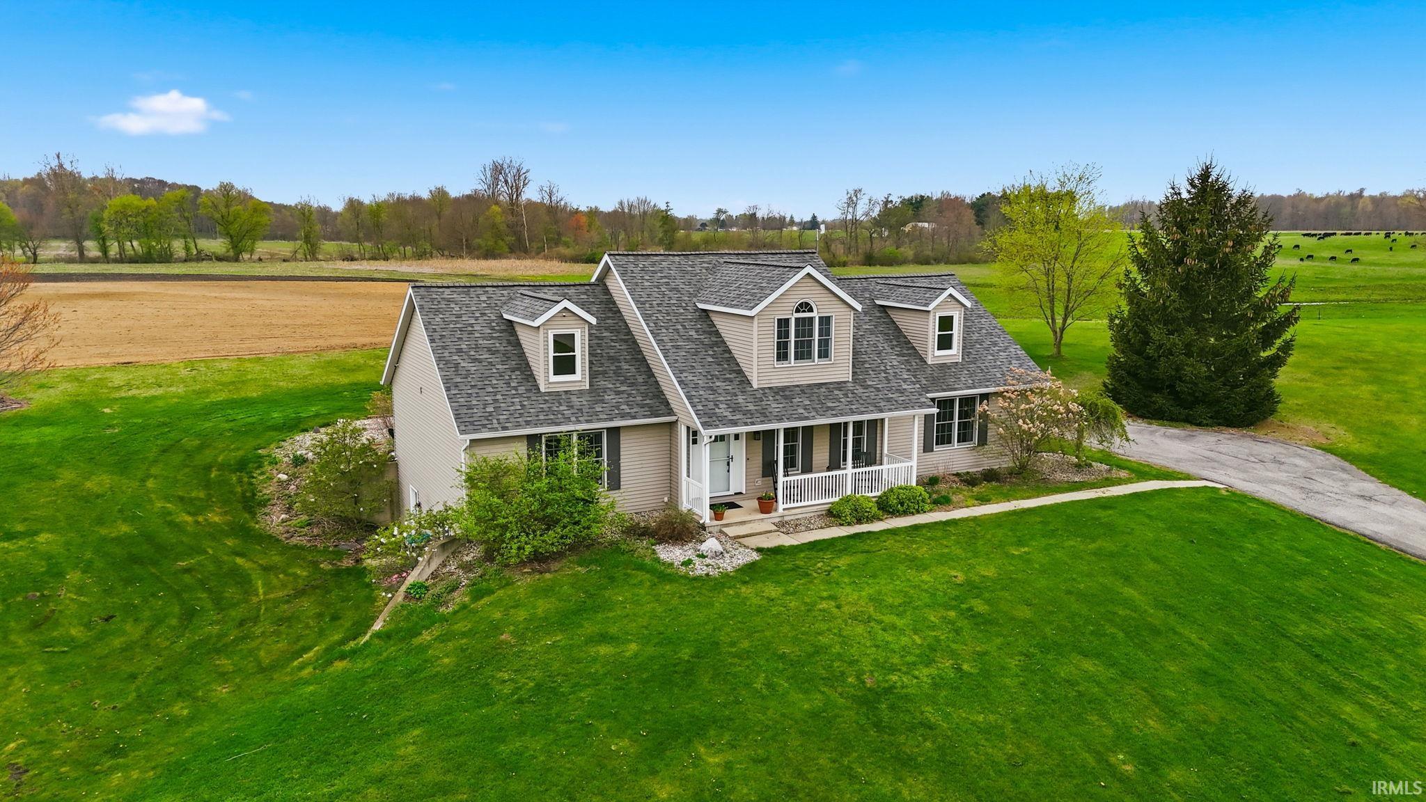 Traditional-style residence featuring dormer windows, a covered front porch, and a gravel driveway