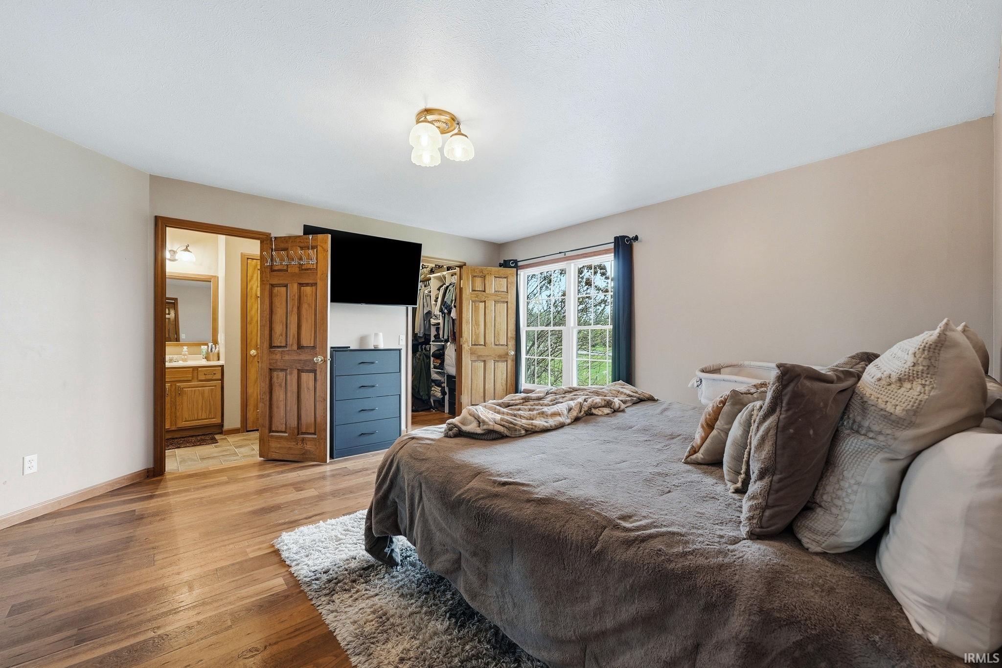 Bedroom with wood-finish flooring, a window offering exterior views, and a ceiling-mounted lighting fixture
