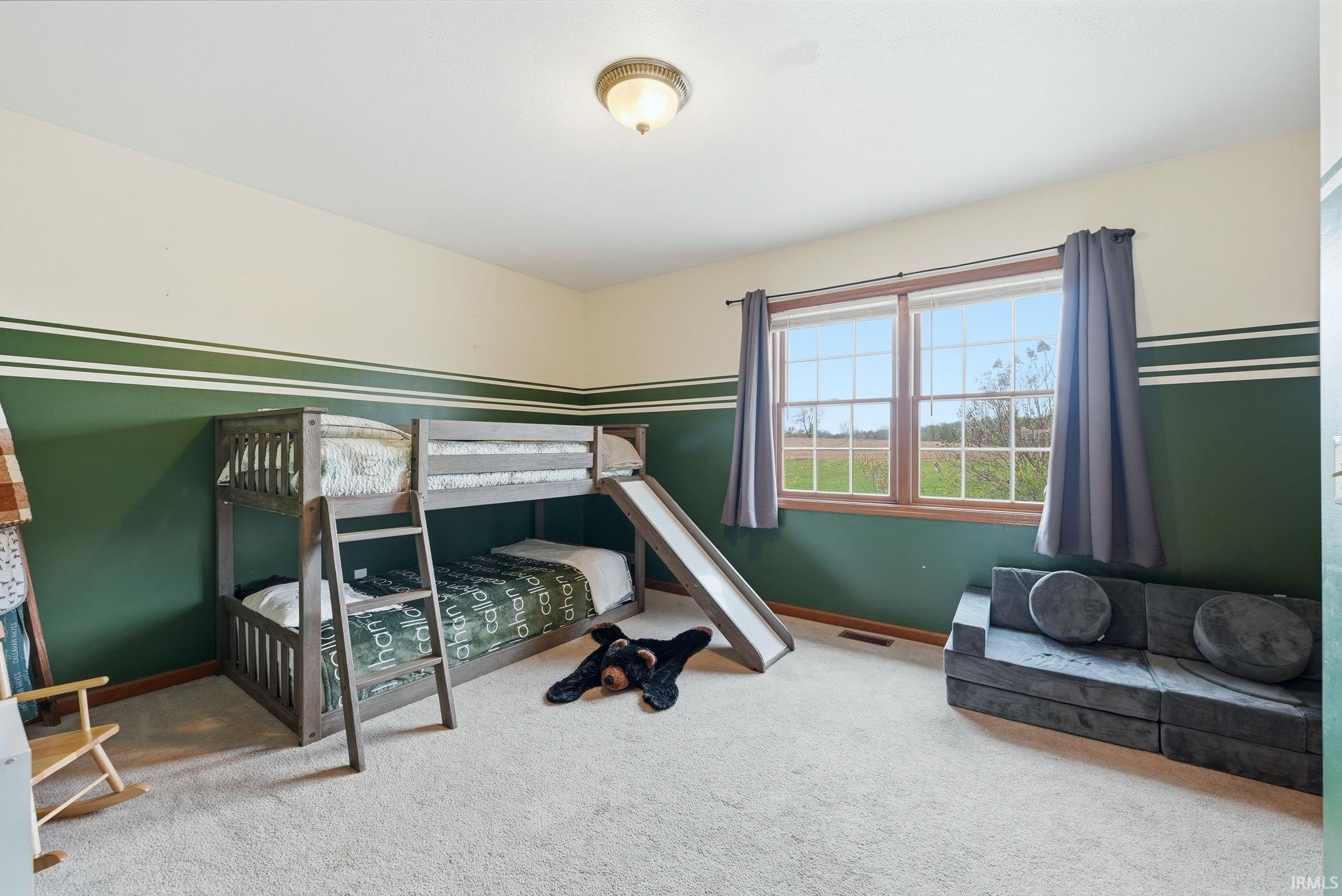 Spacious room featuring neutral carpet flooring and a two-tone wall treatment with a decorative stripe