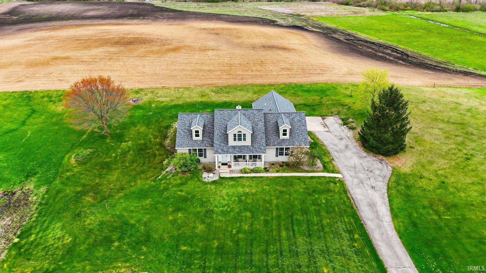Single-family residence featuring a light-colored exterior and a dark gray shingle roof with multiple dormers