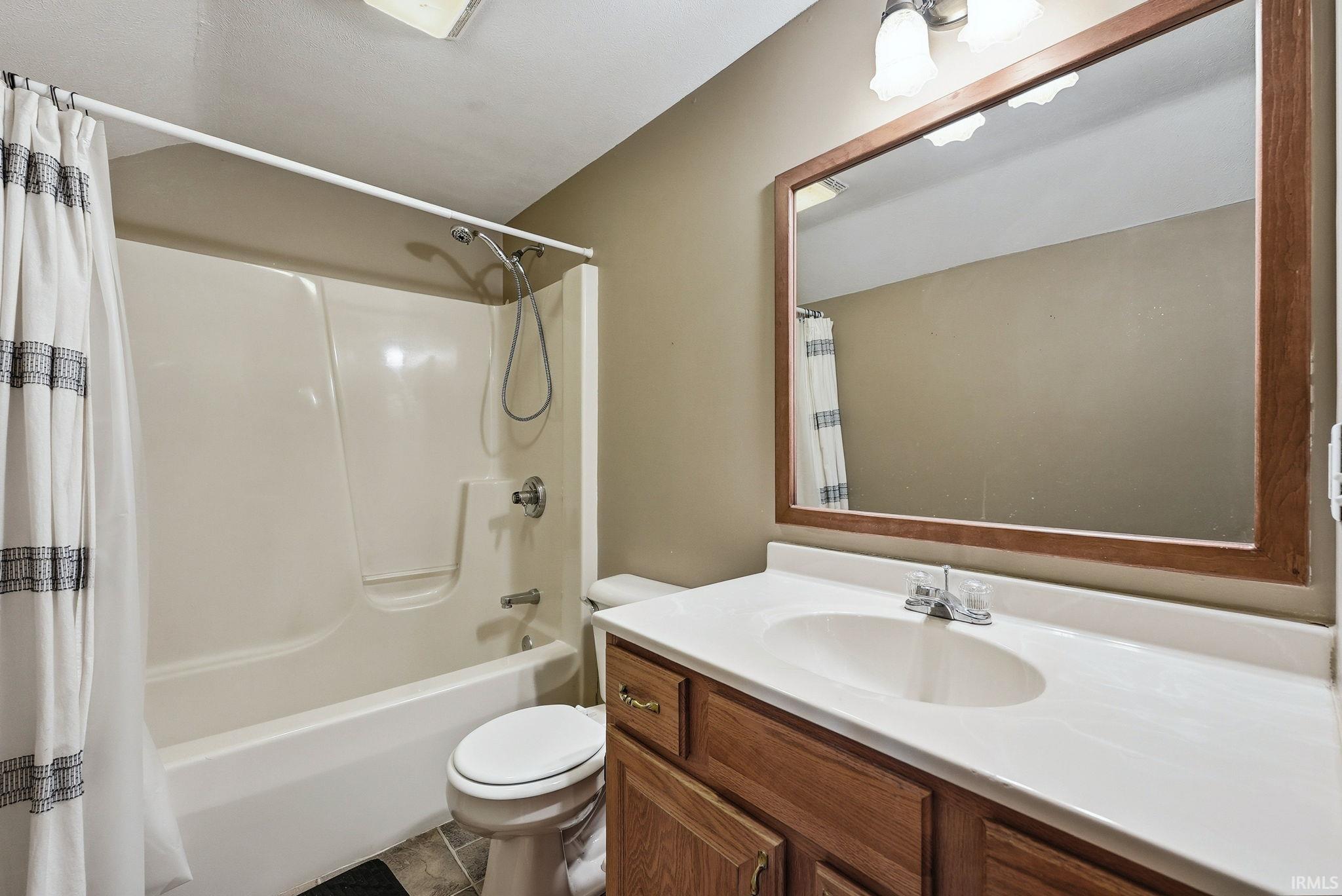Bathroom featuring a vanity with wood-finish cabinetry, a single basin sink, and a framed mirror