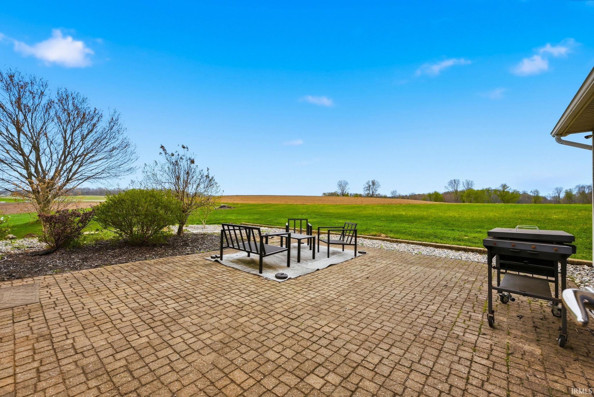 Expansive paver patio with a gravel border and open green space beyond