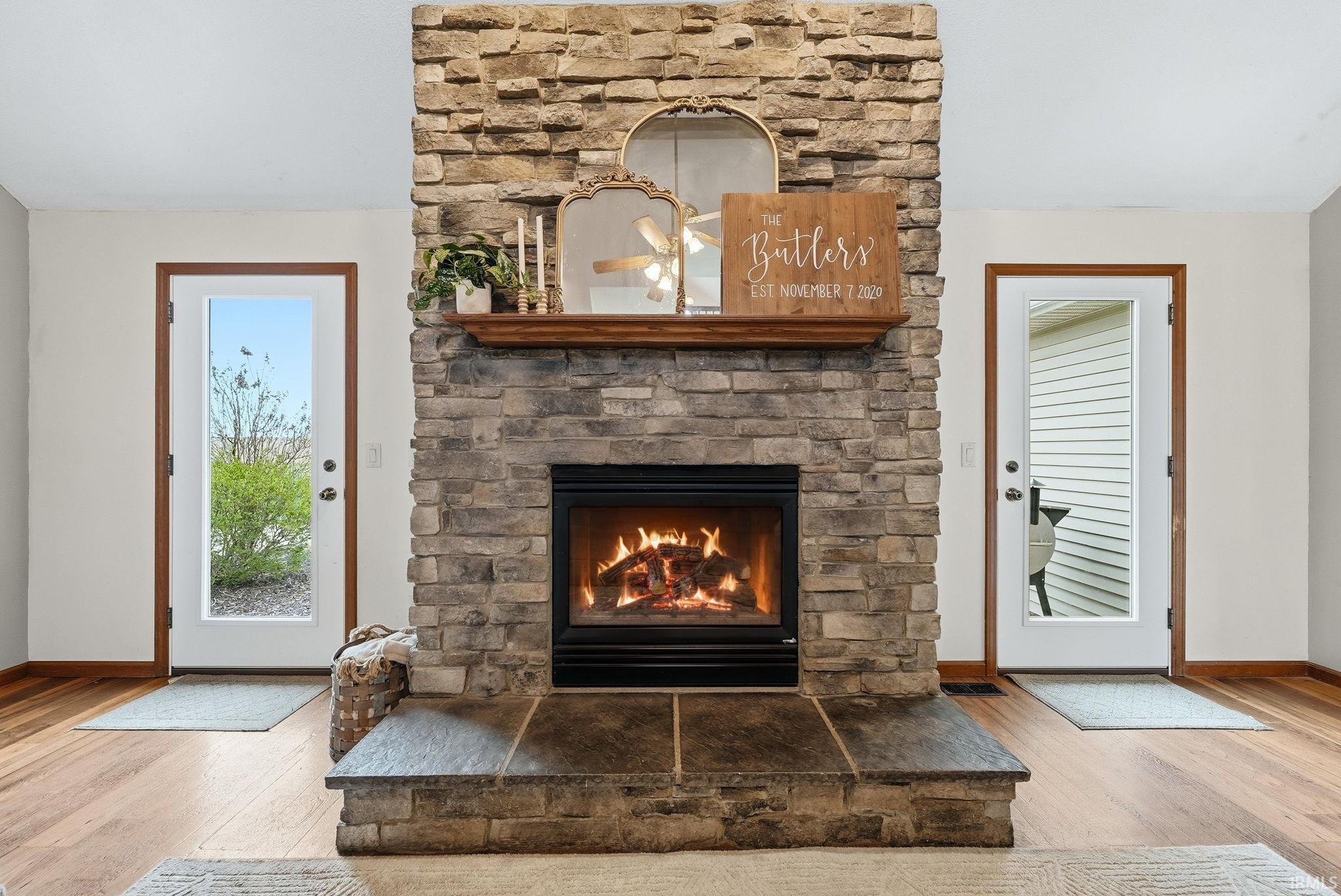 Stone-clad fireplace featuring a gas insert, a substantial wood mantel, and a slate hearth