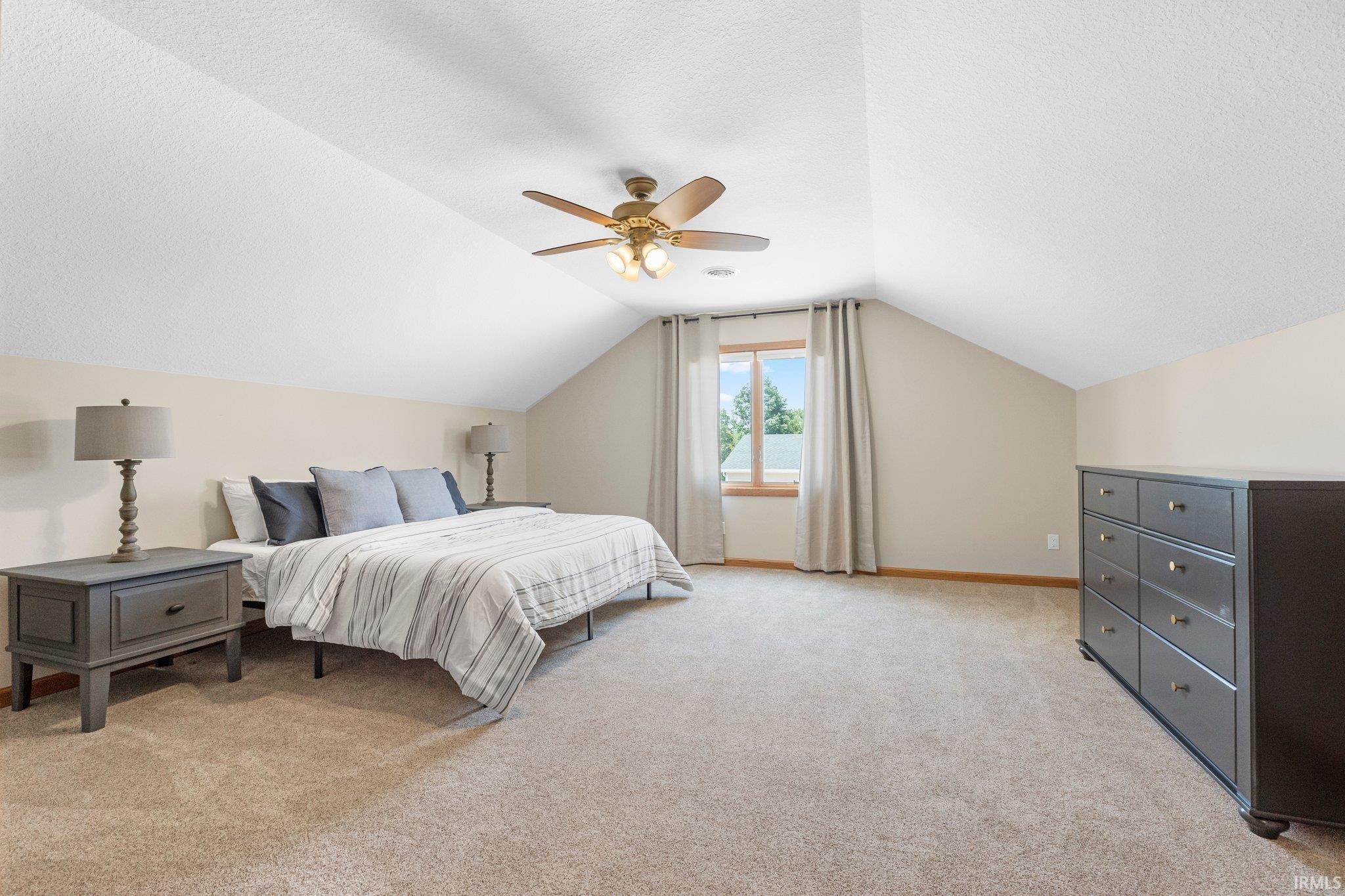 Carpeted room with vaulted ceilings and a ceiling fan