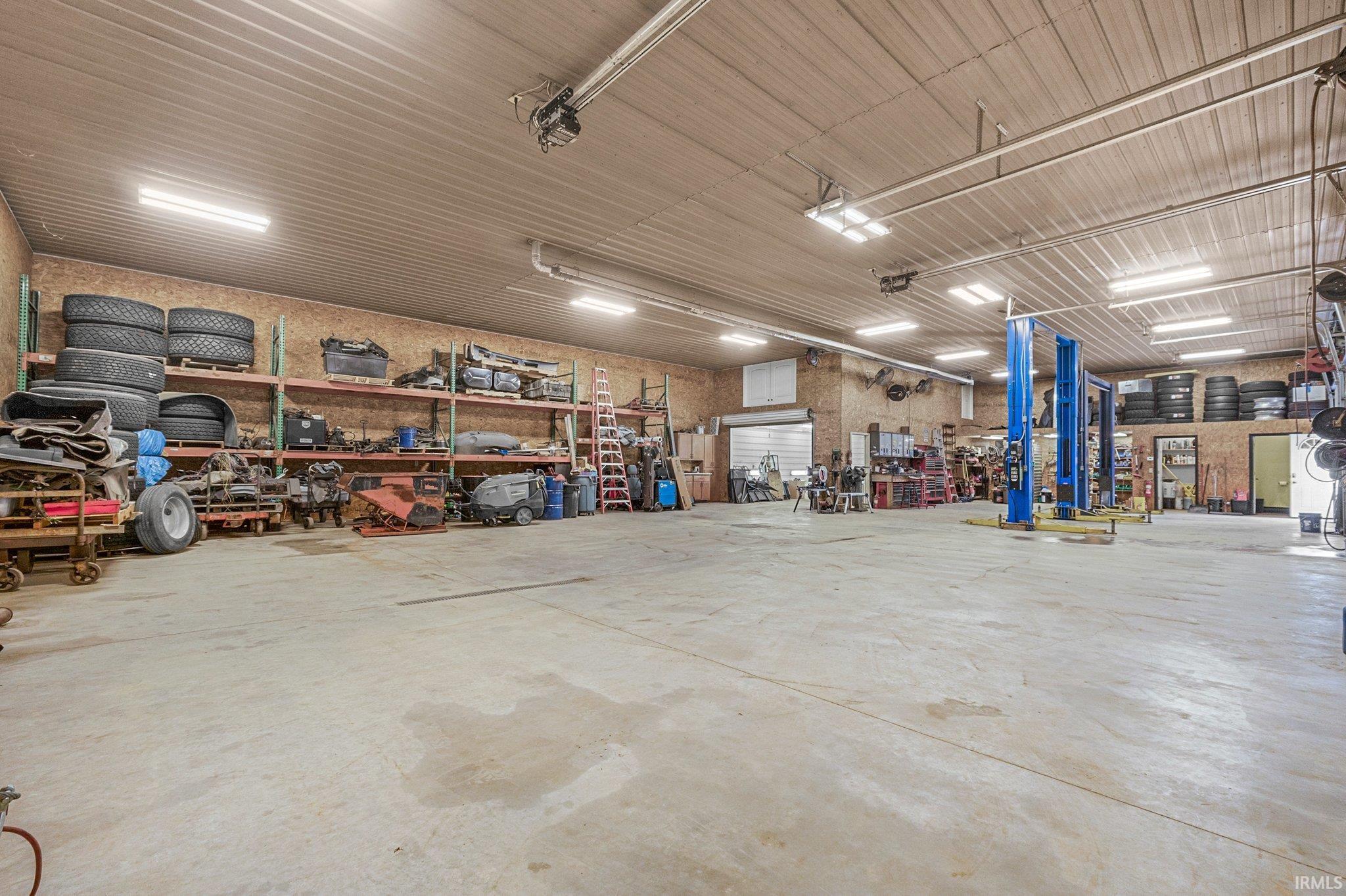 Spacious industrial interior featuring a high corrugated ceiling and fluorescent lighting