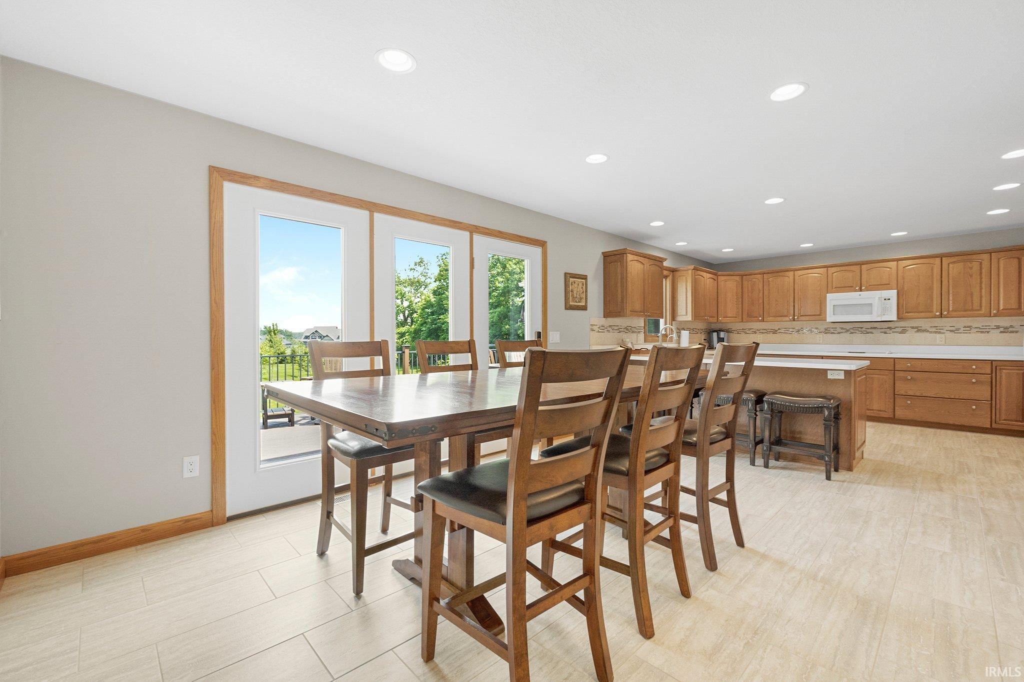 Open-concept kitchen and dining area featuring light wood-finish cabinetry, light countertops, and a tiled backsplash