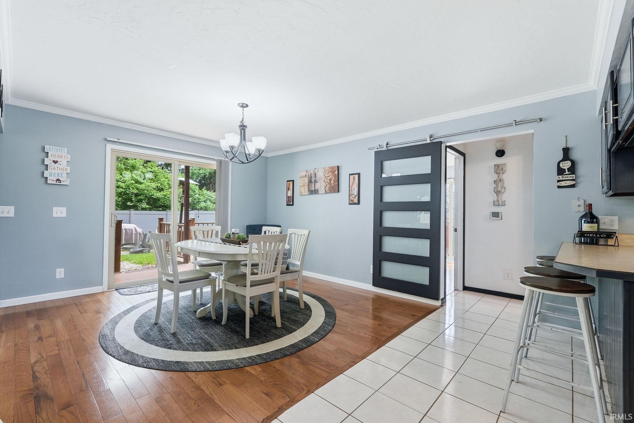 Dining area featuring wood-finish flooring, a contemporary chandelier, and a sliding glass door providing access to the outdoors