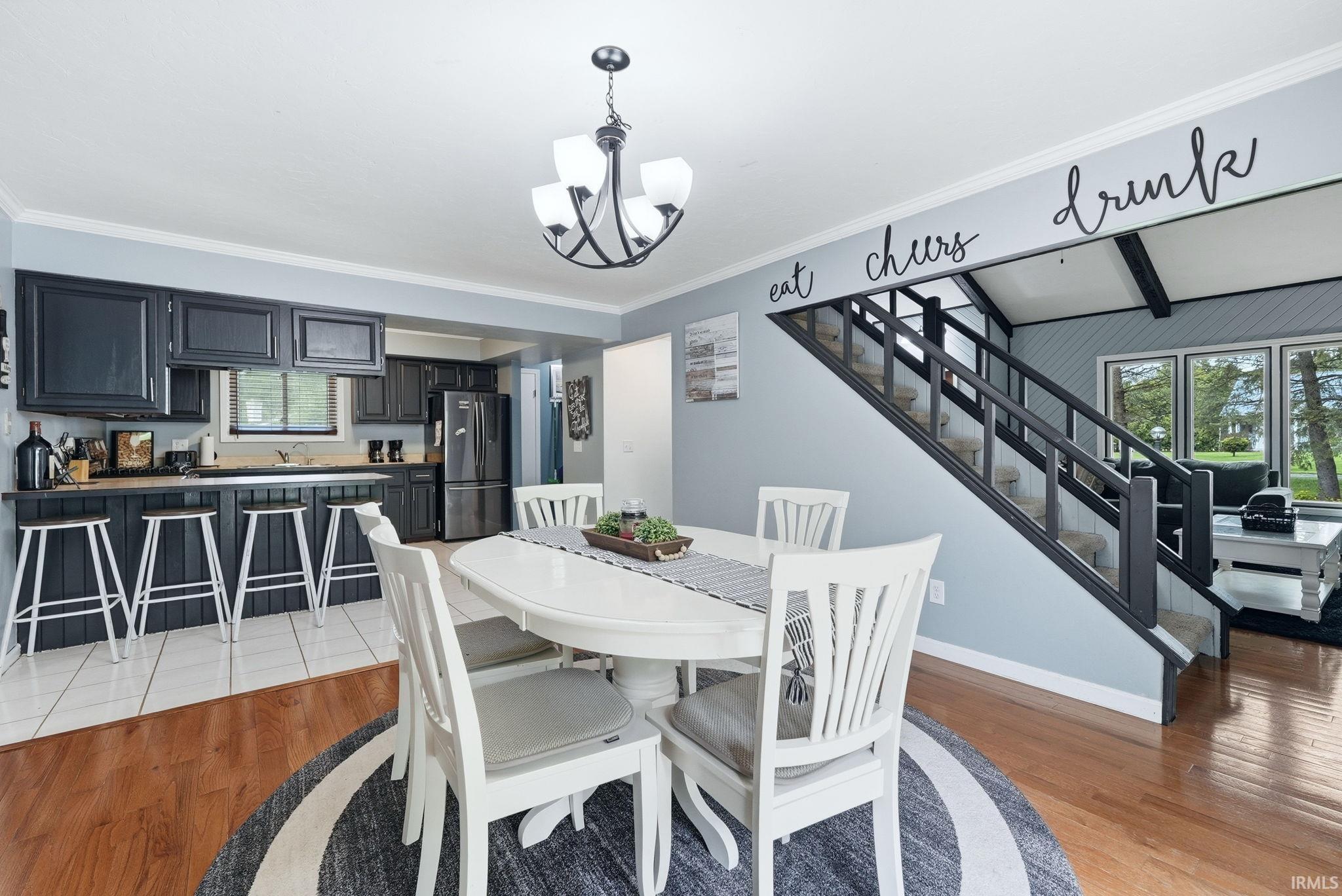 Open-concept dining area featuring a contemporary chandelier, wood-finish flooring, and direct access to the kitchen
