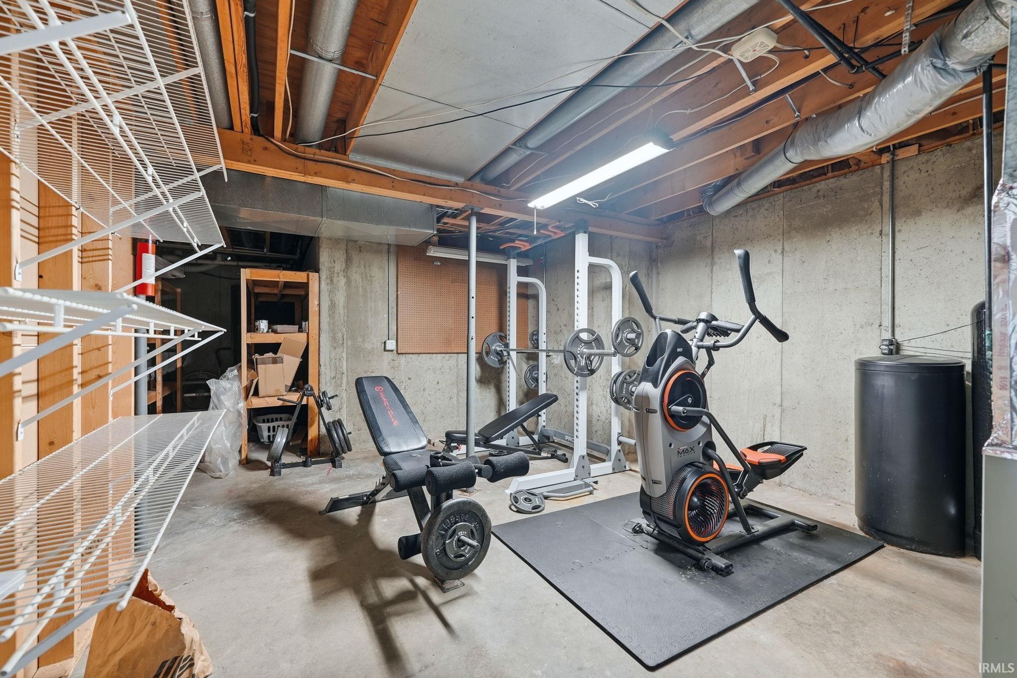 Unfinished basement area featuring exposed concrete walls and ceiling joists