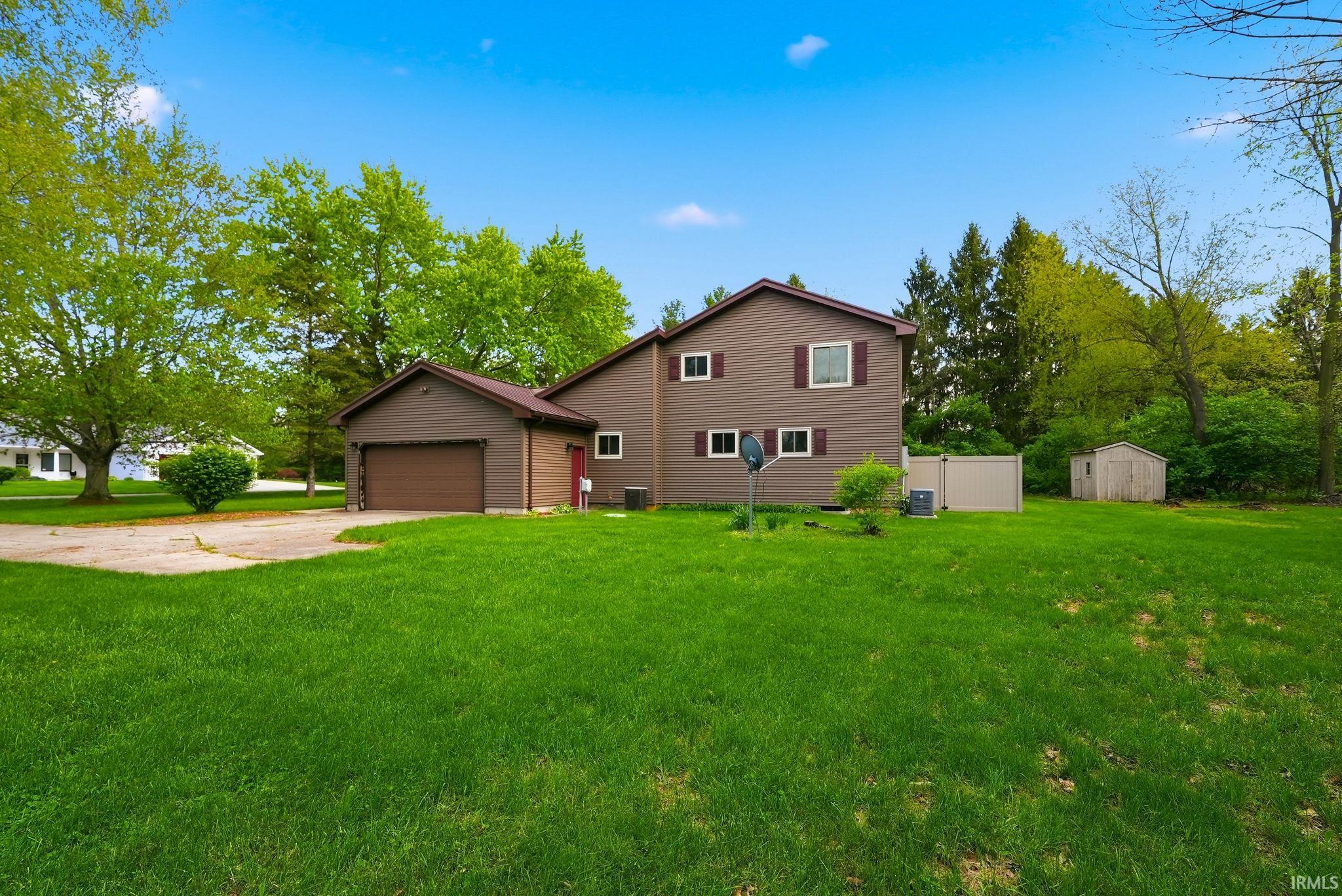 Brown two-story residence featuring an attached garage and red shutters