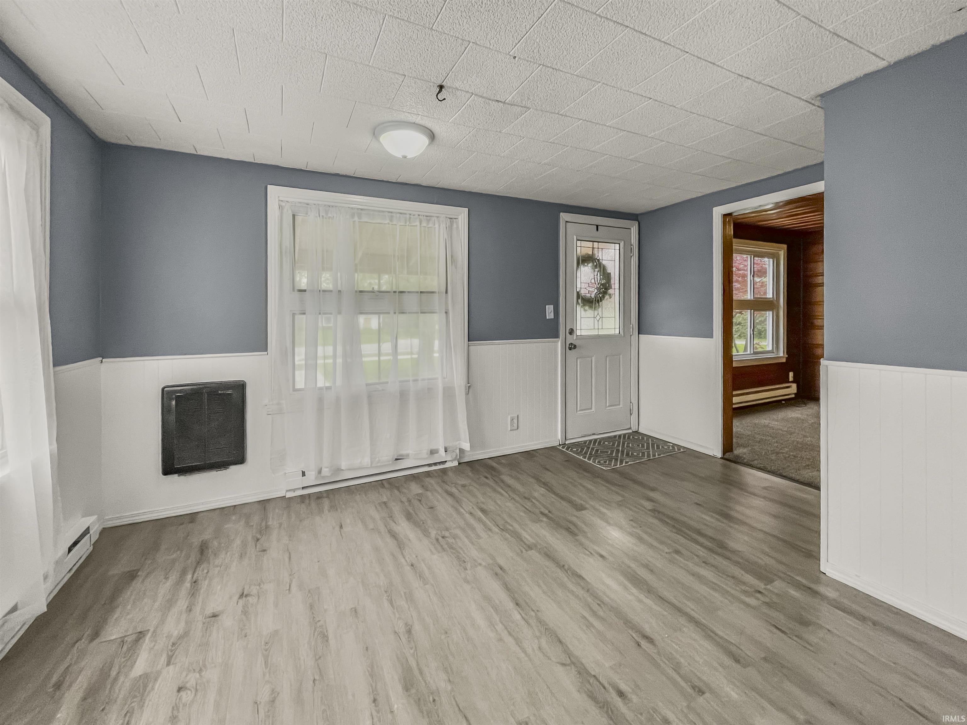 Living area with wood-finish flooring, wainscoting, and a neutral color palette
